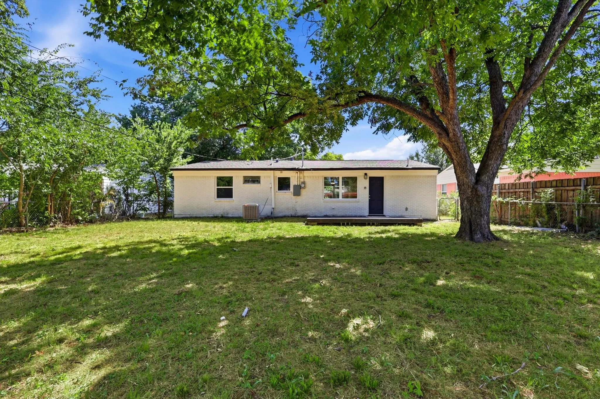 Expansive green lawn with mature trees providing natural shading