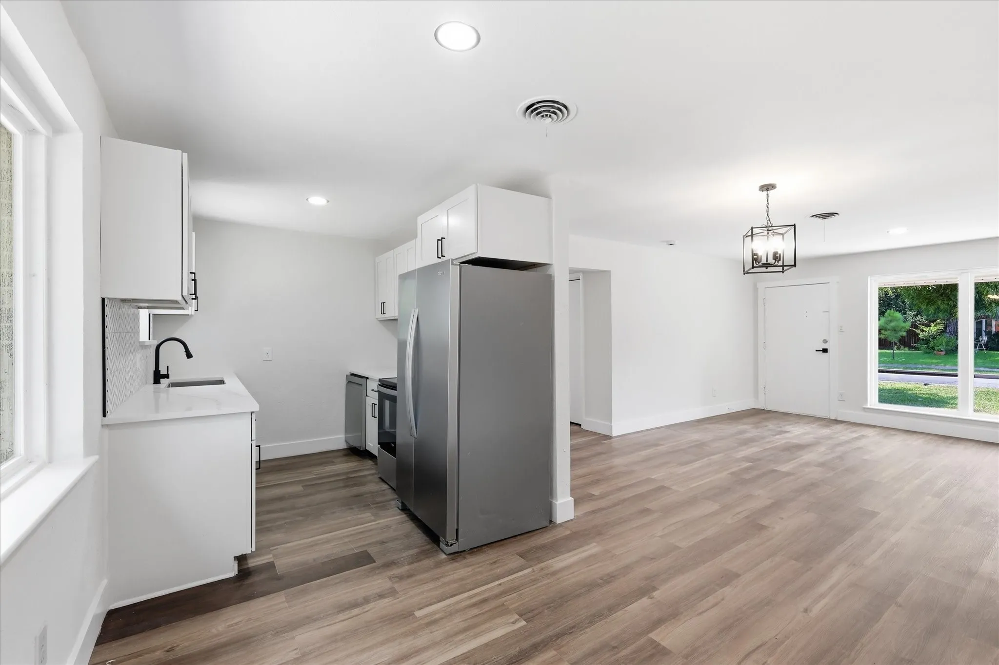 Open-concept living area featuring wood-finish flooring, recessed lighting, and a contemporary chandelier