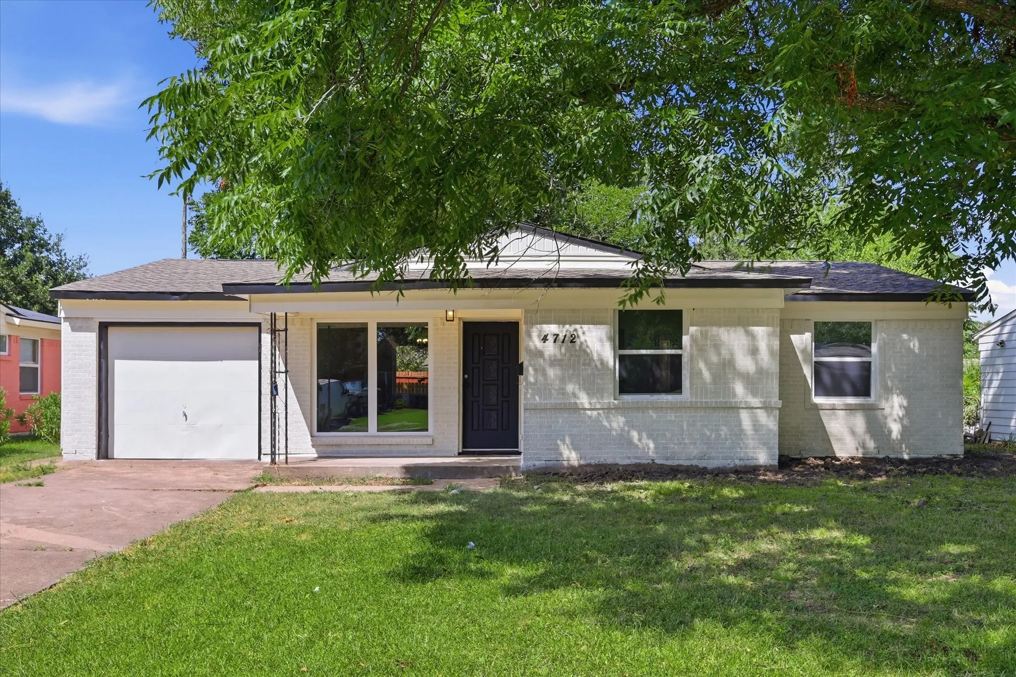 Single-story residence featuring a painted brick exterior, a dark entry door, and a single-car garage