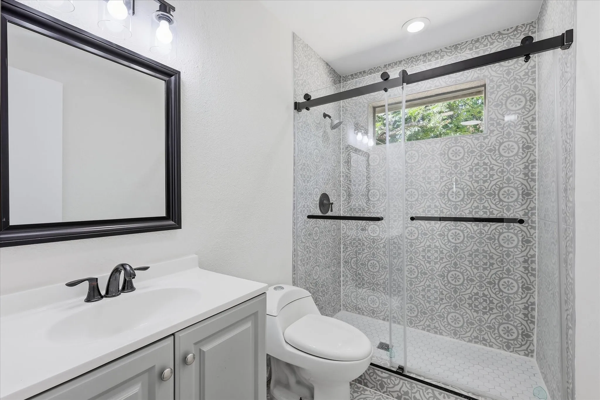 Bathroom featuring a floating vanity with an integrated sink, black framed mirror, and matte black fixtures