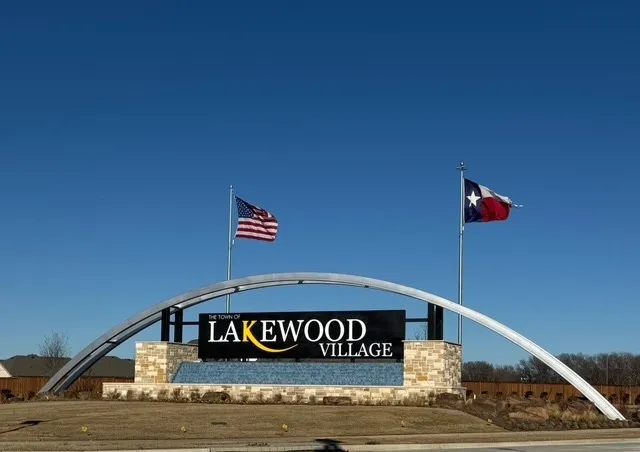 Community entry sign featuring stacked stone and a curved metal archway