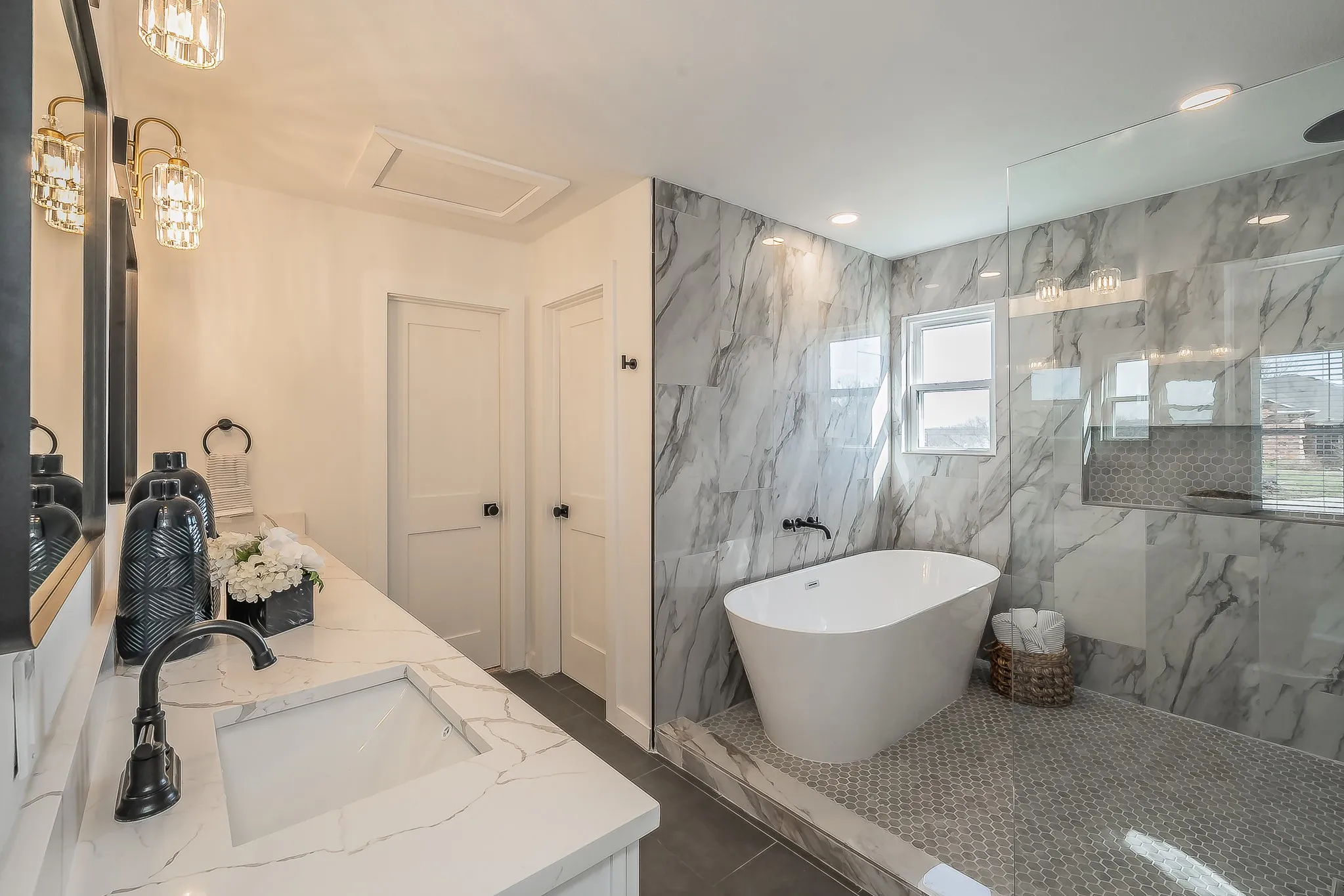 Freestanding soaking tub with marble-look wall tiling and a glass-enclosed shower