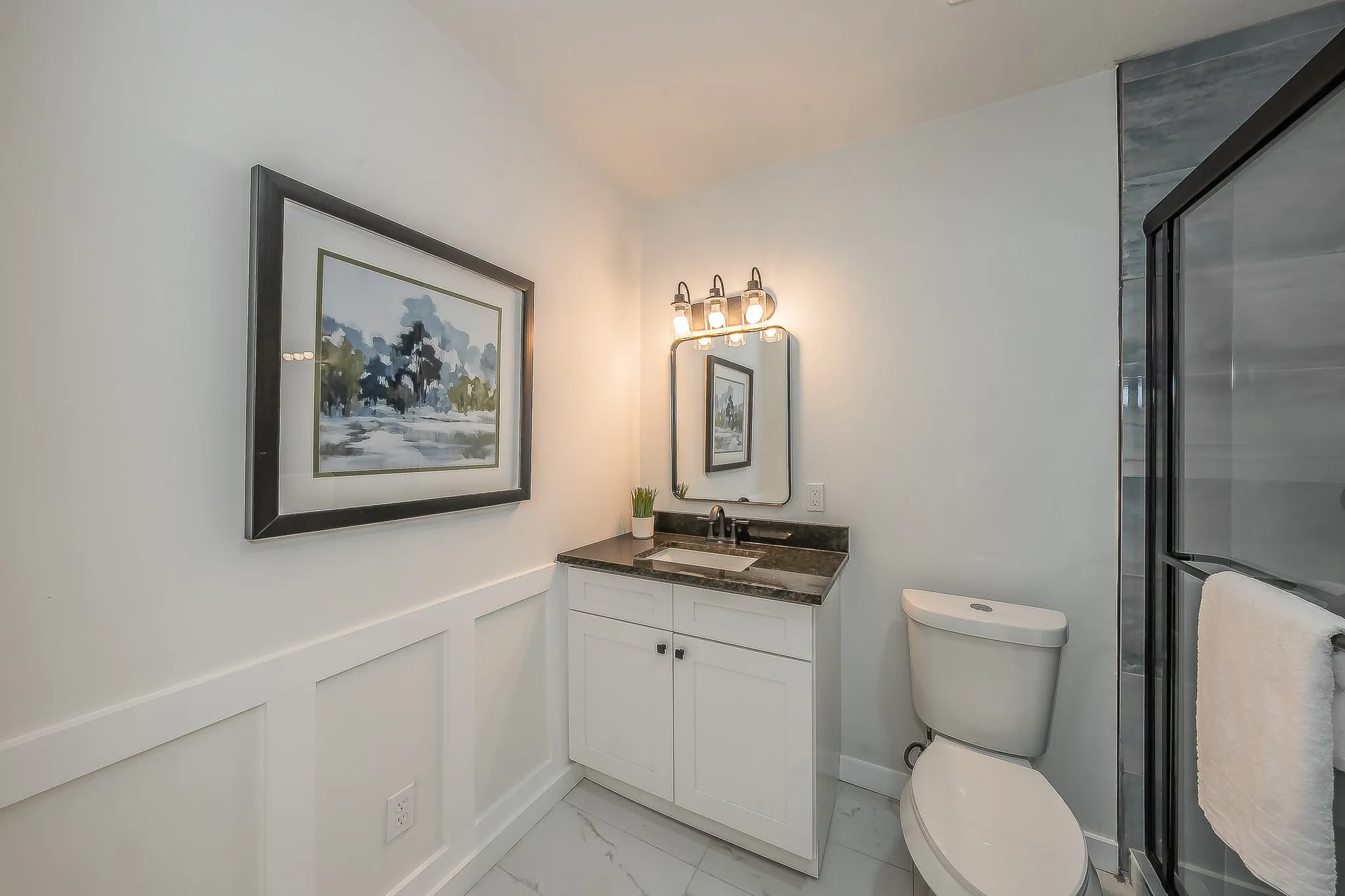 Full bathroom featuring a single vanity with a stone countertop, a framed mirror, and a glass-enclosed shower