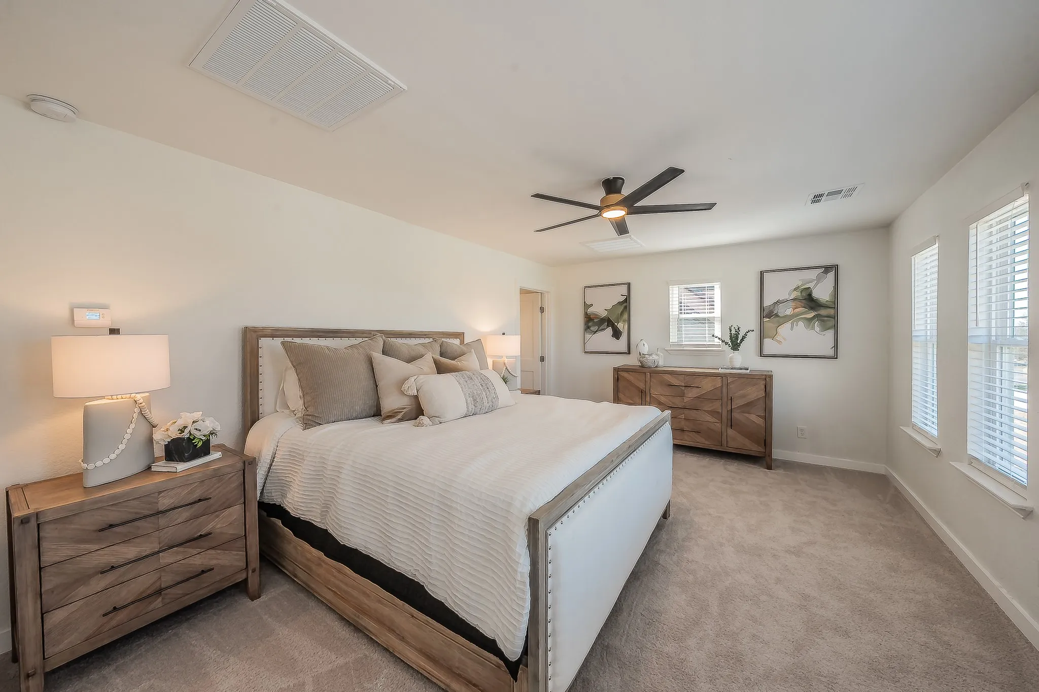 Spacious room featuring neutral carpeting, light-toned walls, and multiple windows with blinds