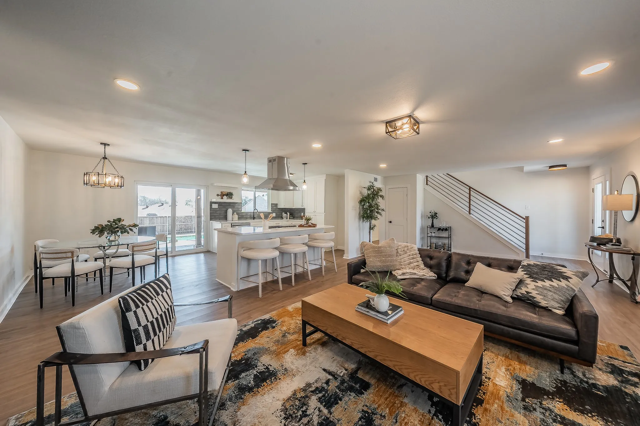 Open-concept living space featuring wood-finish flooring, recessed lighting, and a modern kitchen with a large island