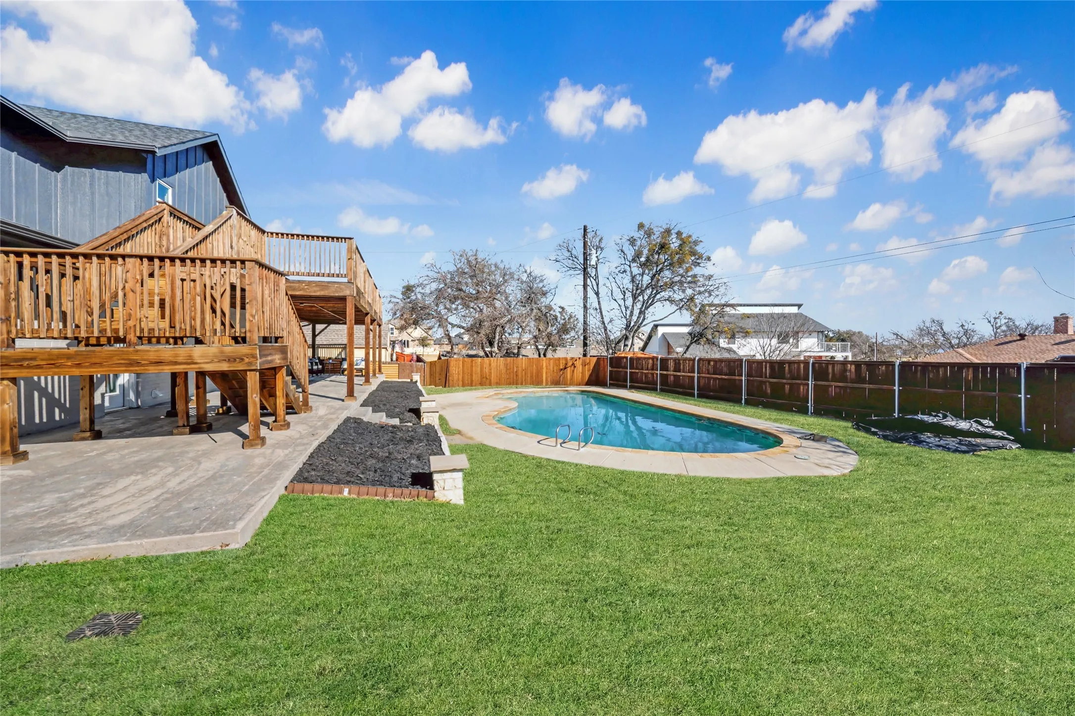 Backyard featuring a freeform swimming pool, expansive lawn, and a multi-level wood deck structure
