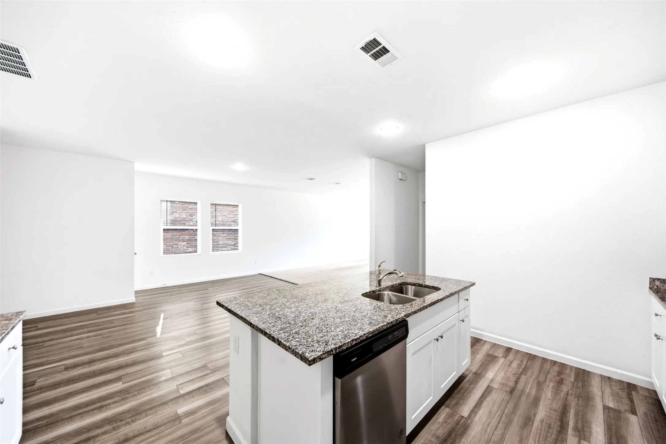 Kitchen island with granite countertop, double basin sink, and stainless steel dishwasher