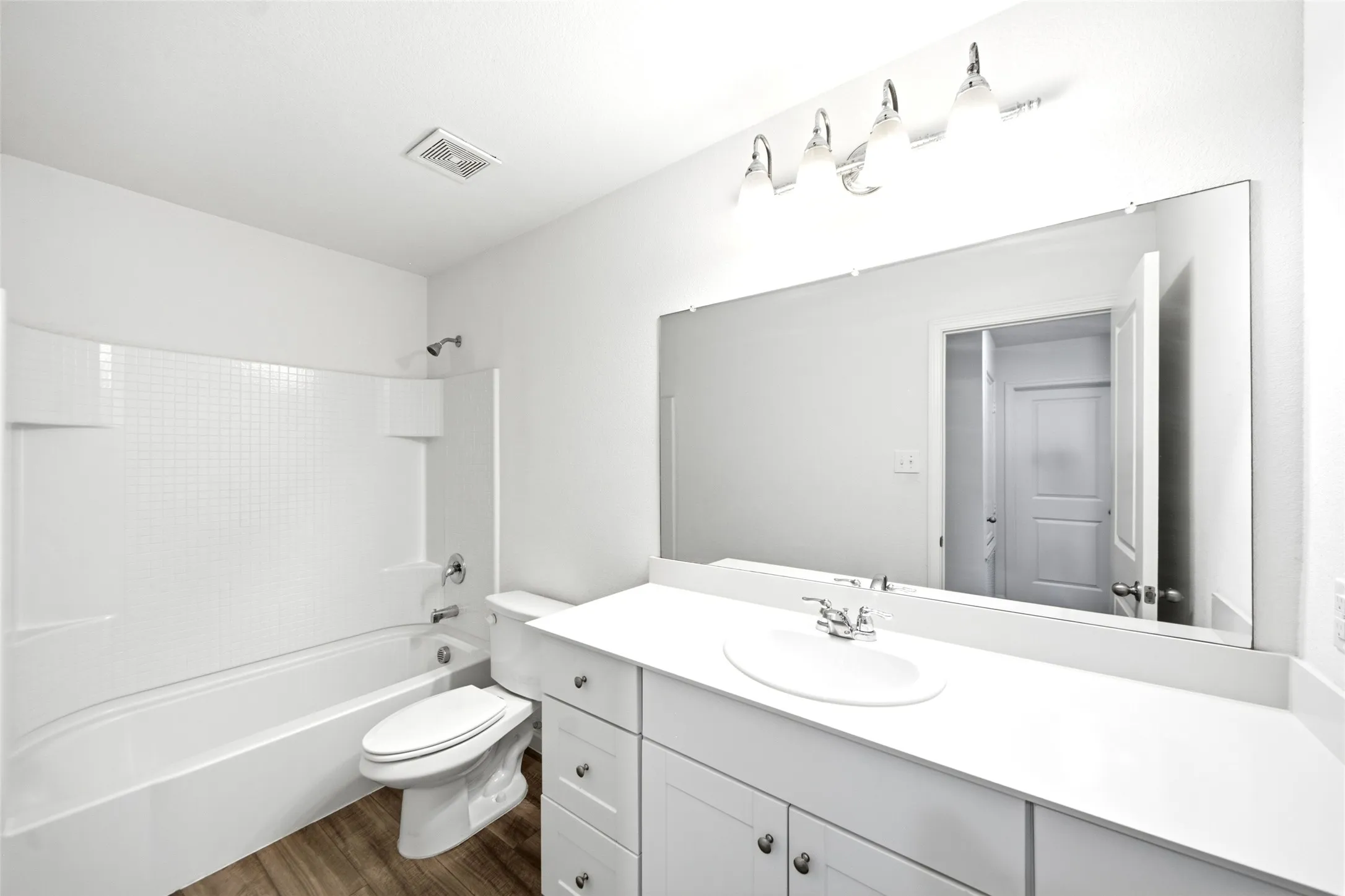 White vanity with shaker-style cabinetry, an integrated sink, and an expansive wall-mounted mirror