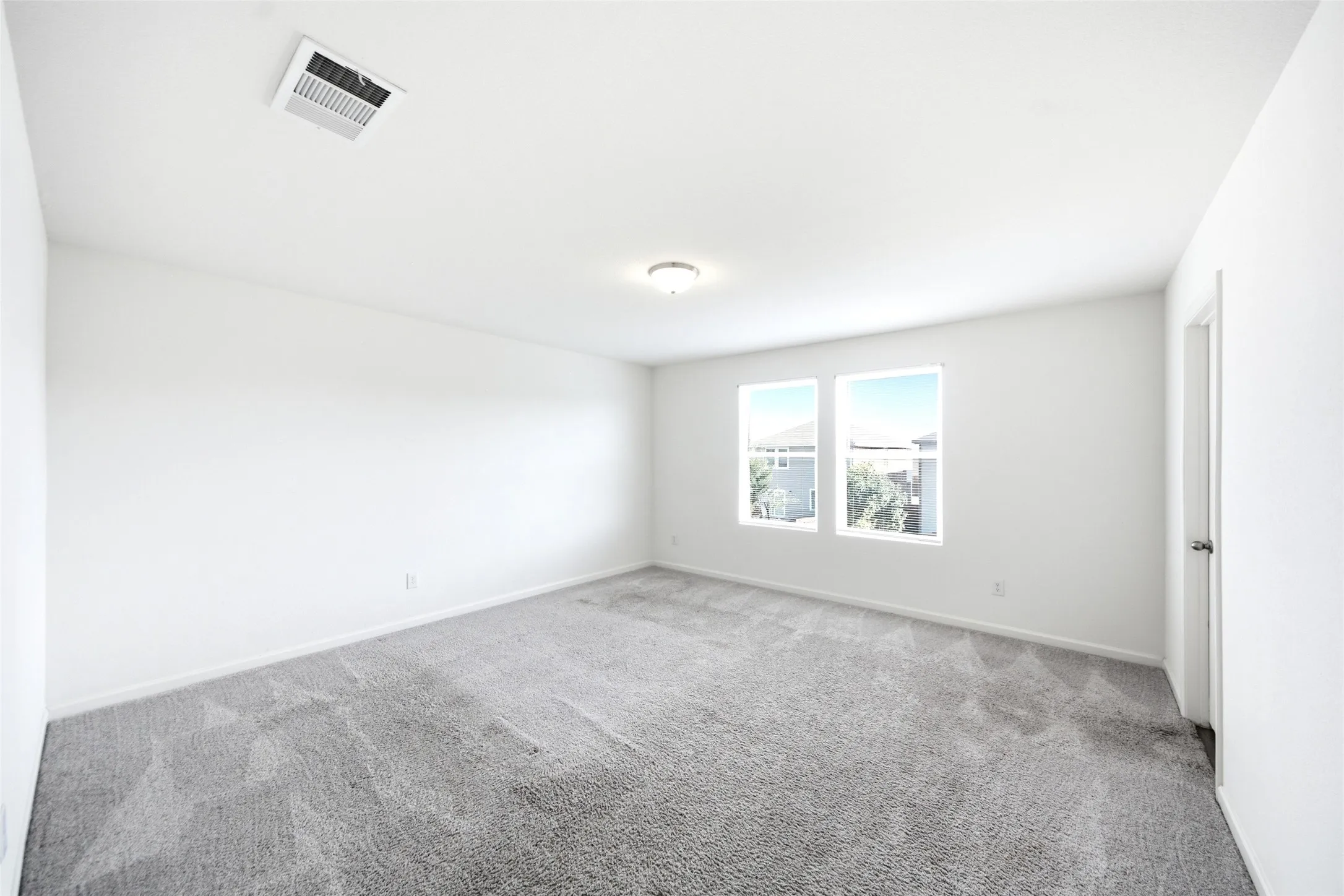 Recessed ceiling light fixture, twin windows, wall-to-wall carpeting, white walls, and a white ceiling