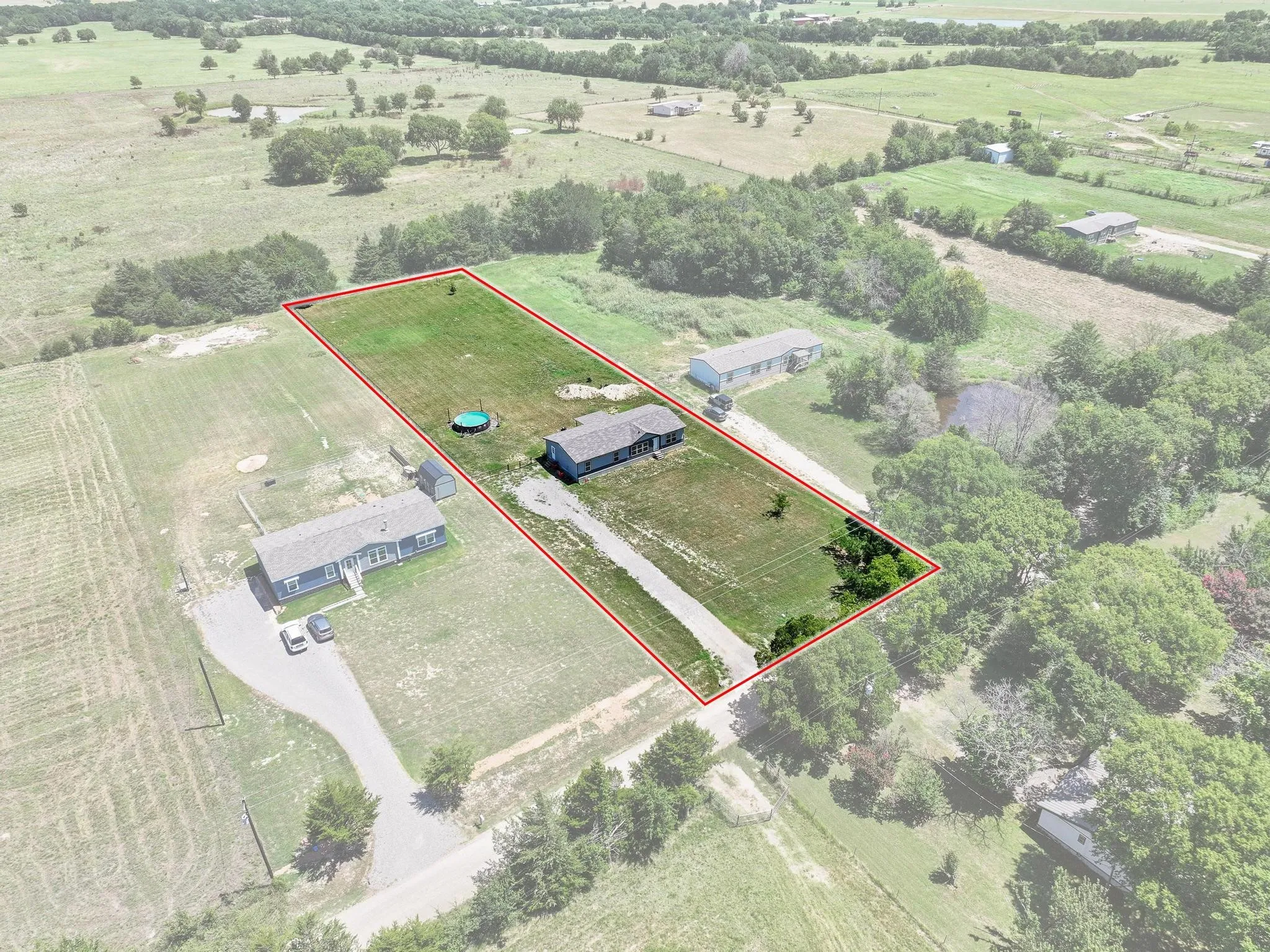 Expansive property featuring a single-story residence, a detached auxiliary building, and a lengthy driveway