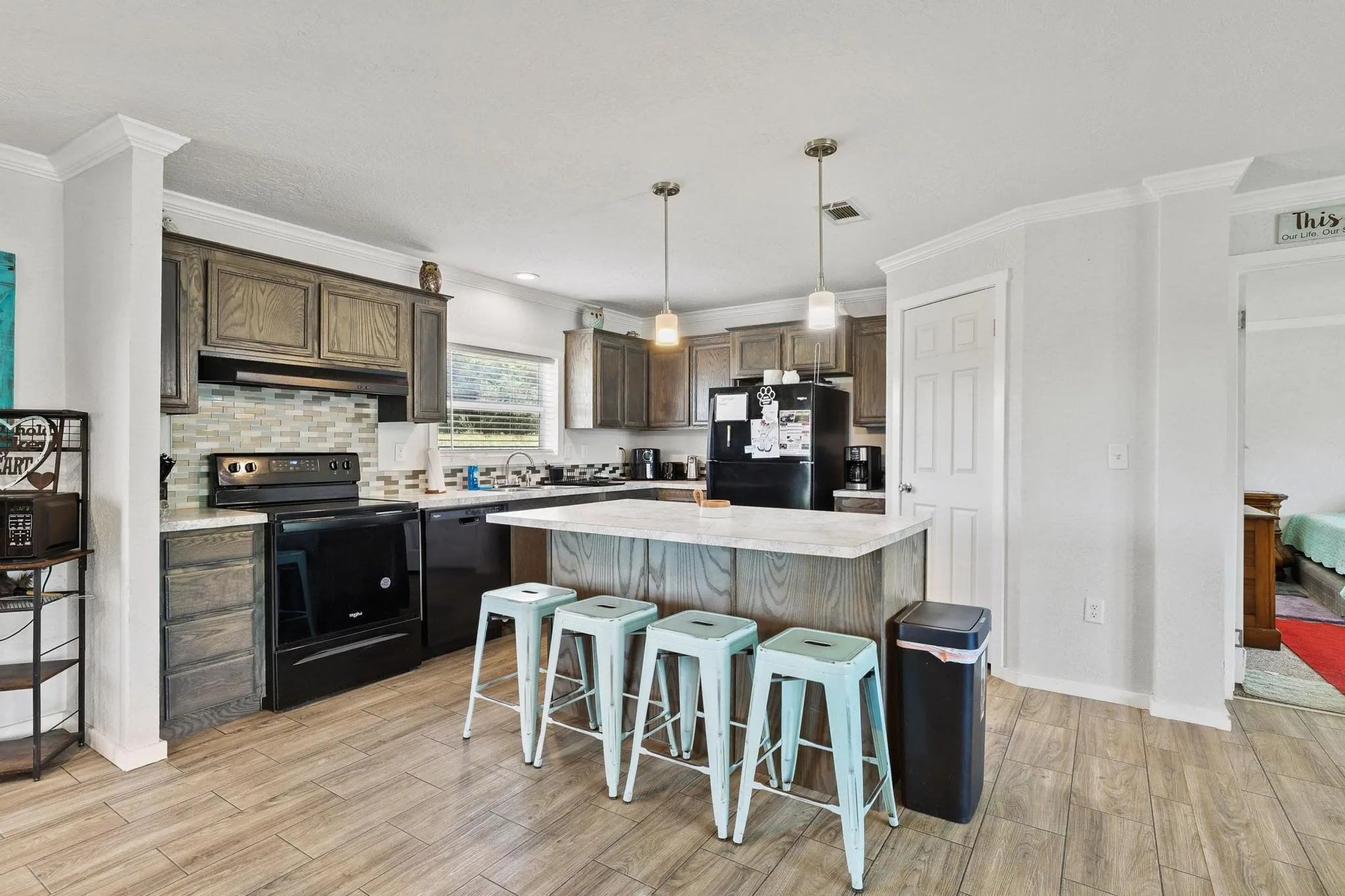 Kitchen featuring wood-finish flooring, an island with countertop seating, dark wood cabinetry, and a mosaic tile backsplash
