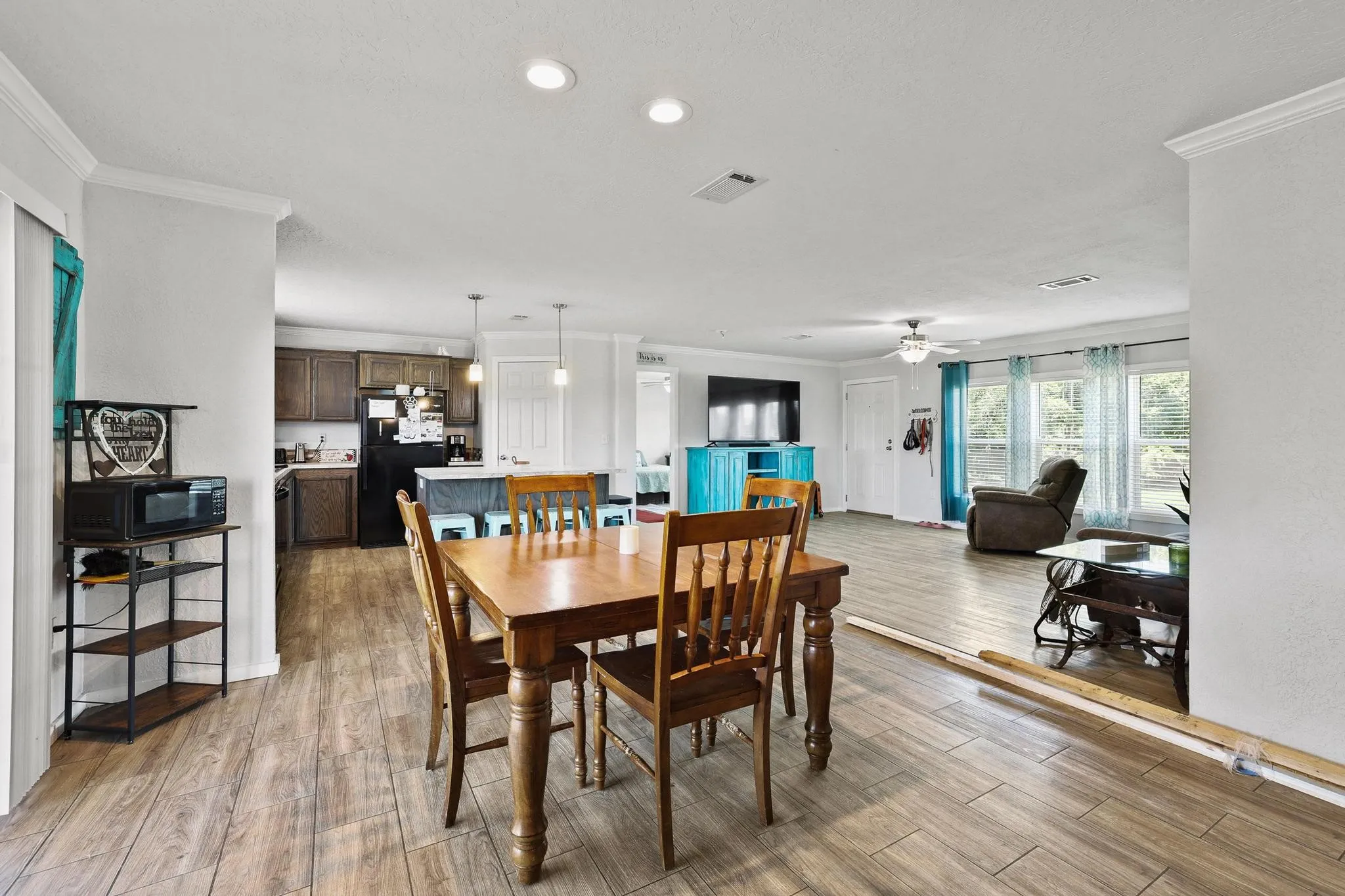 Open-concept living space with wood-finish flooring, recessed lighting, and crown molding