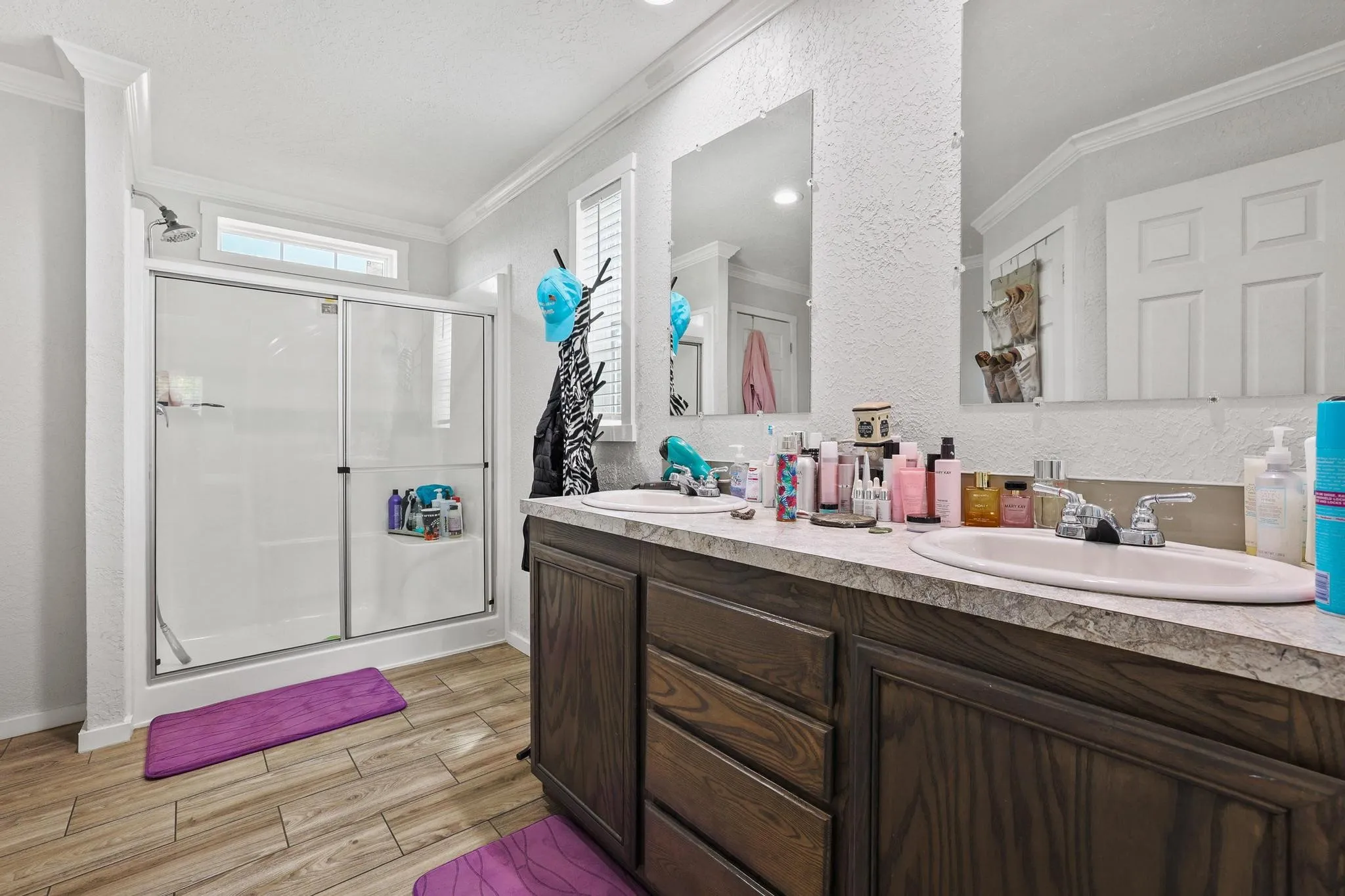 Bathroom featuring a dual vanity with a wood-finish cabinet, integrated sinks, and individual wall-mounted mirrors