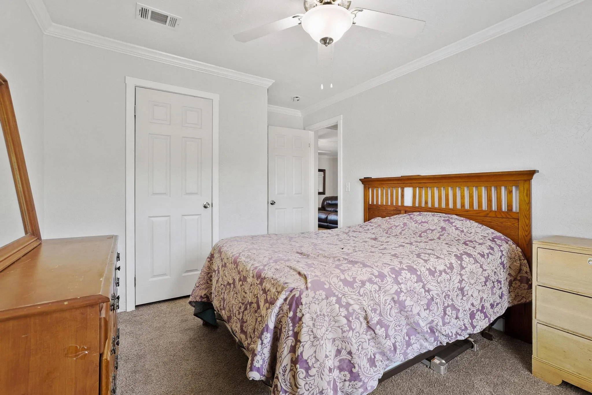 Carpeted room featuring a ceiling fan with integrated lighting, white crown molding, white four-panel doors, and neutral wall paint