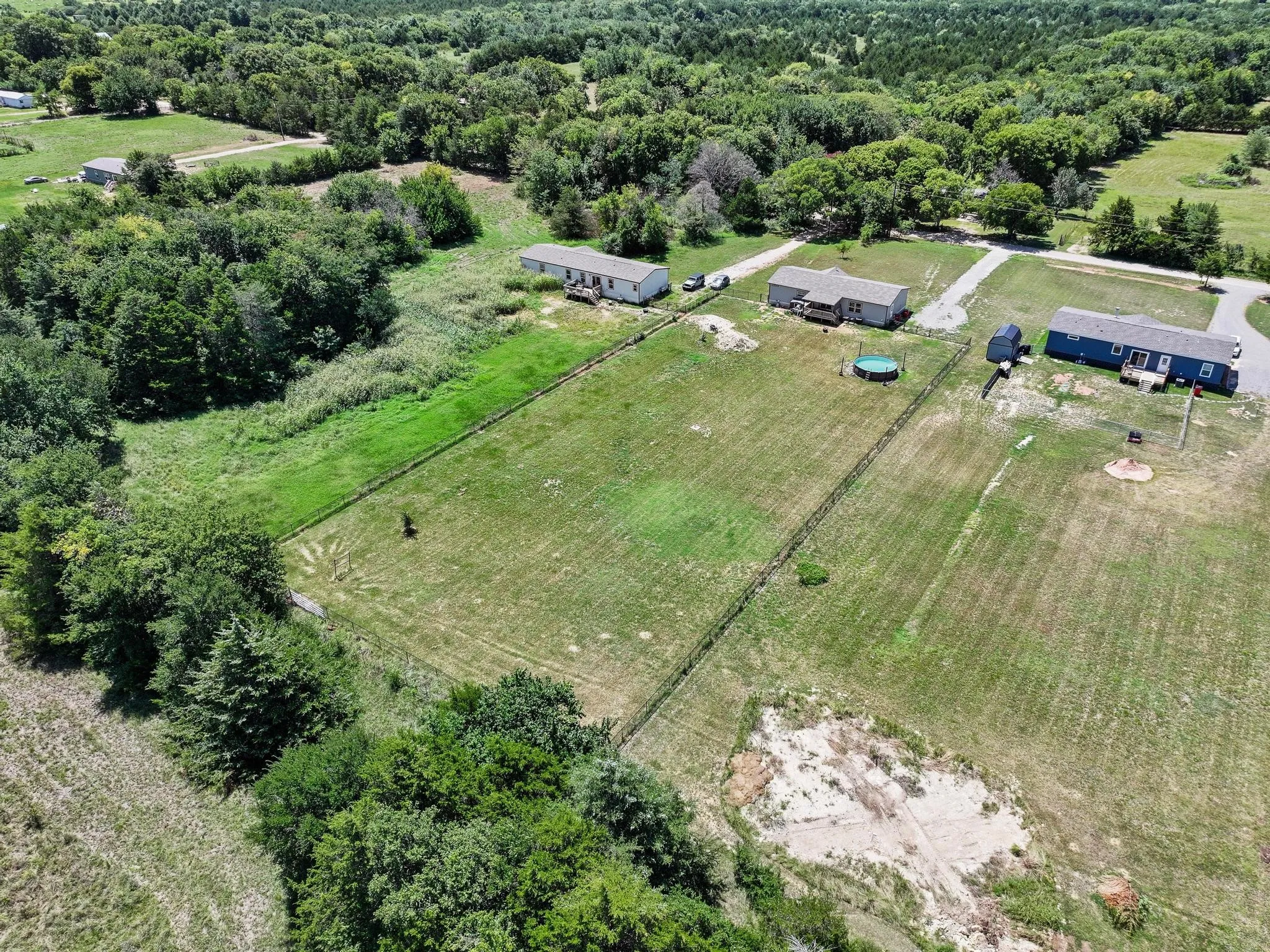 Expansive property featuring three distinct structures with surrounding green spaces