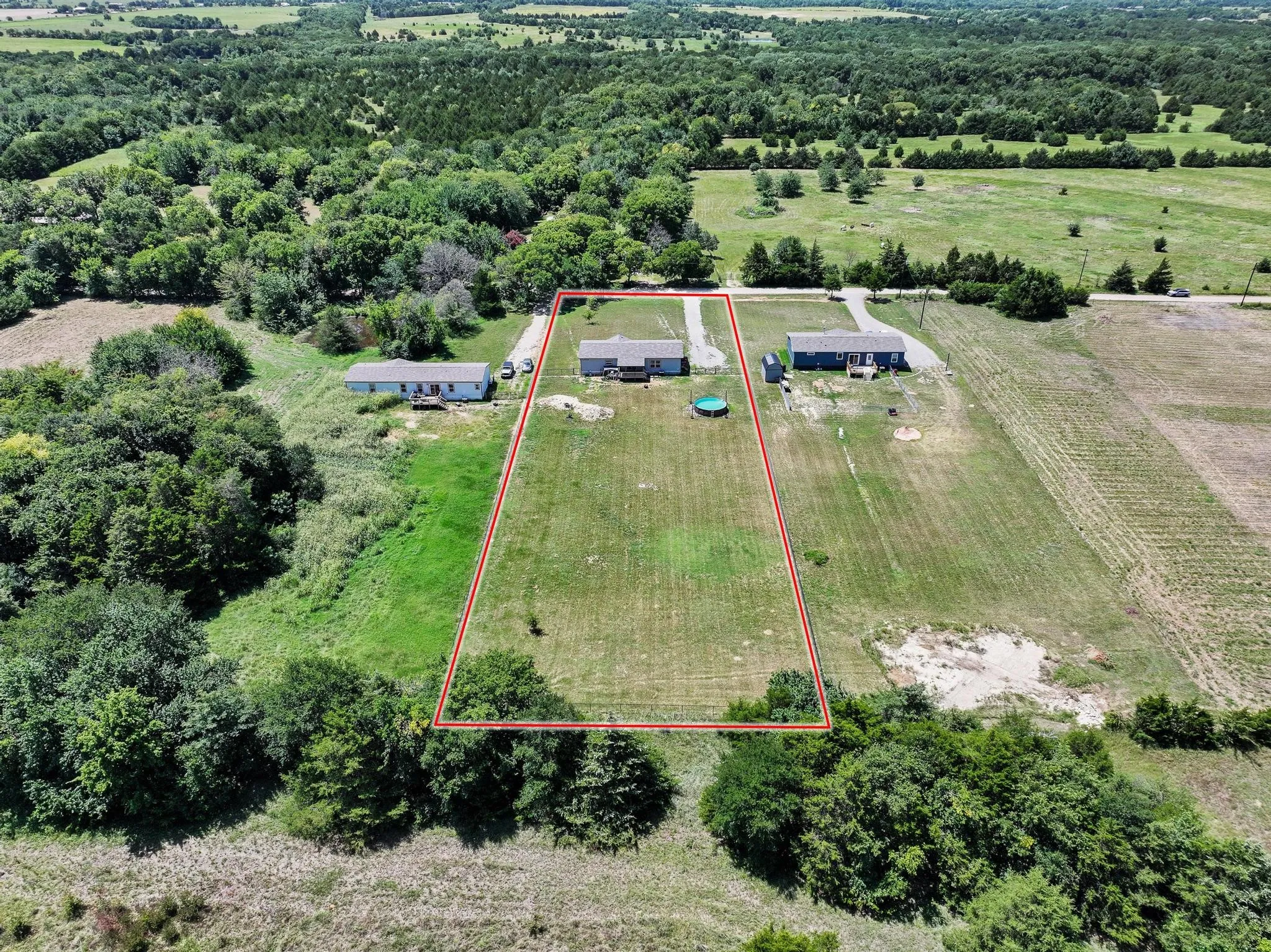 Expansive rural property featuring an established structure, generous cleared land, and mature perimeter trees