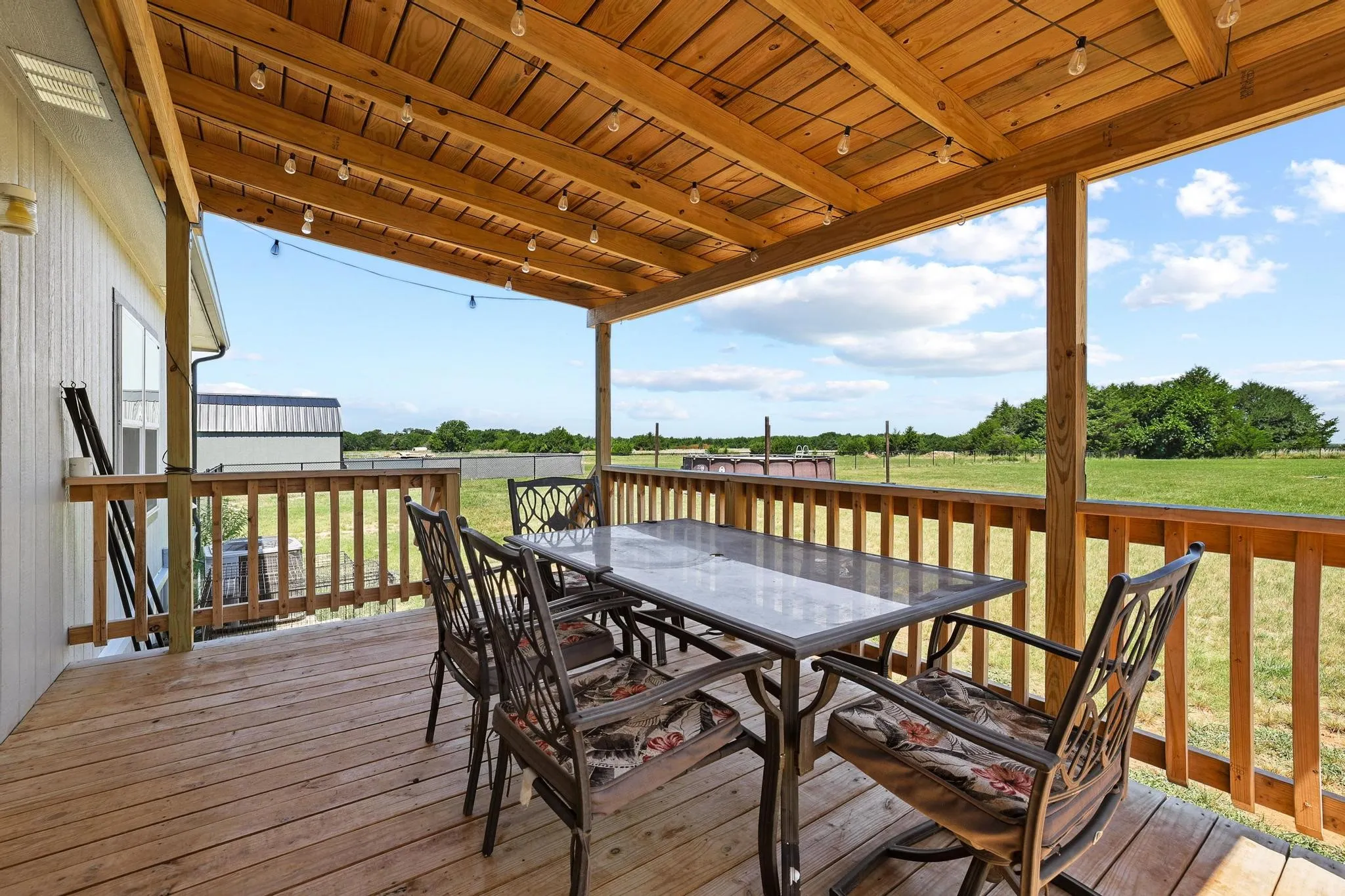 Spacious wood-finish deck with a solid wood beam ceiling and recessed string lighting