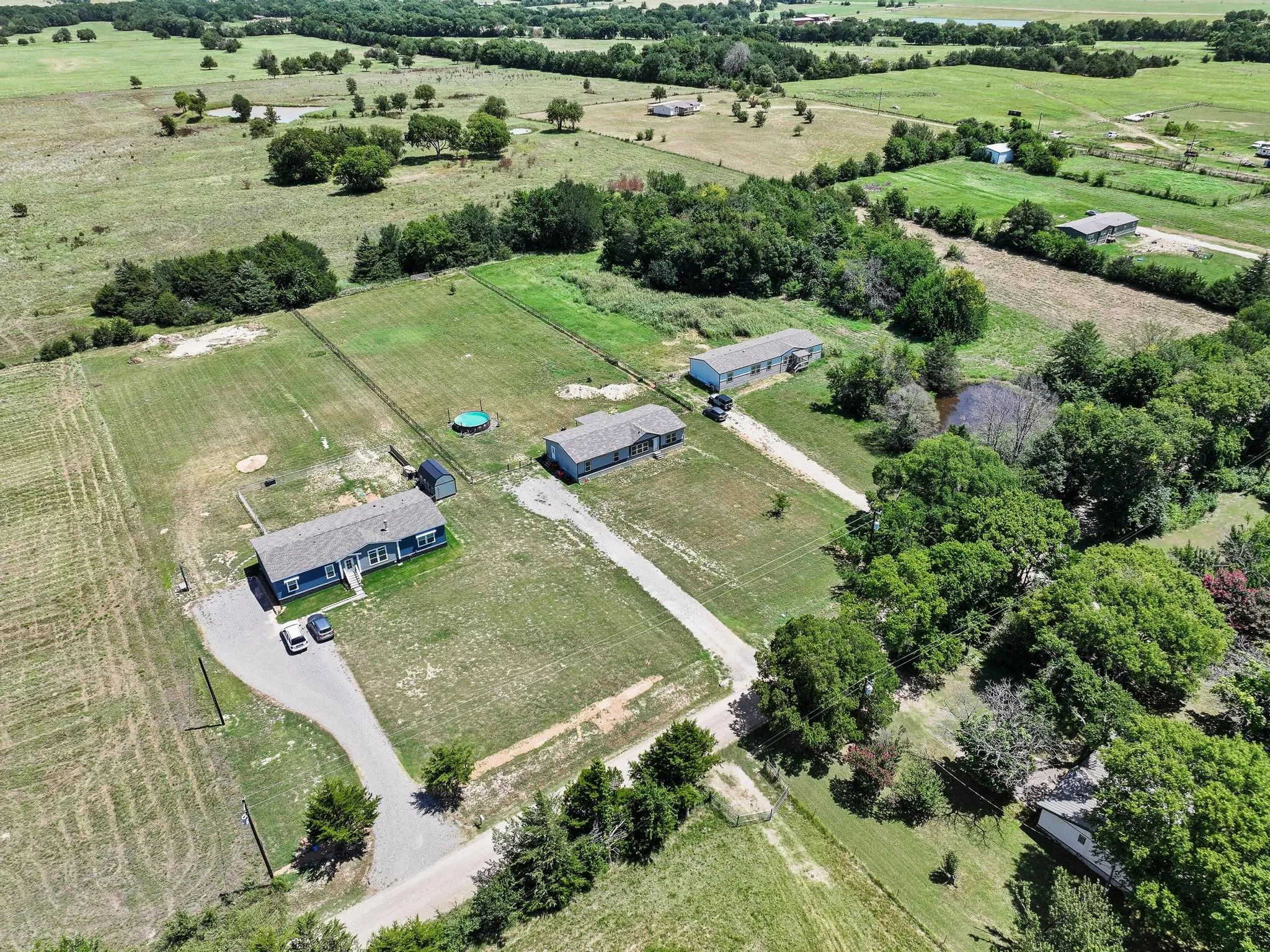 Expansive rural property featuring multiple residences, a private pond, and mature tree lines