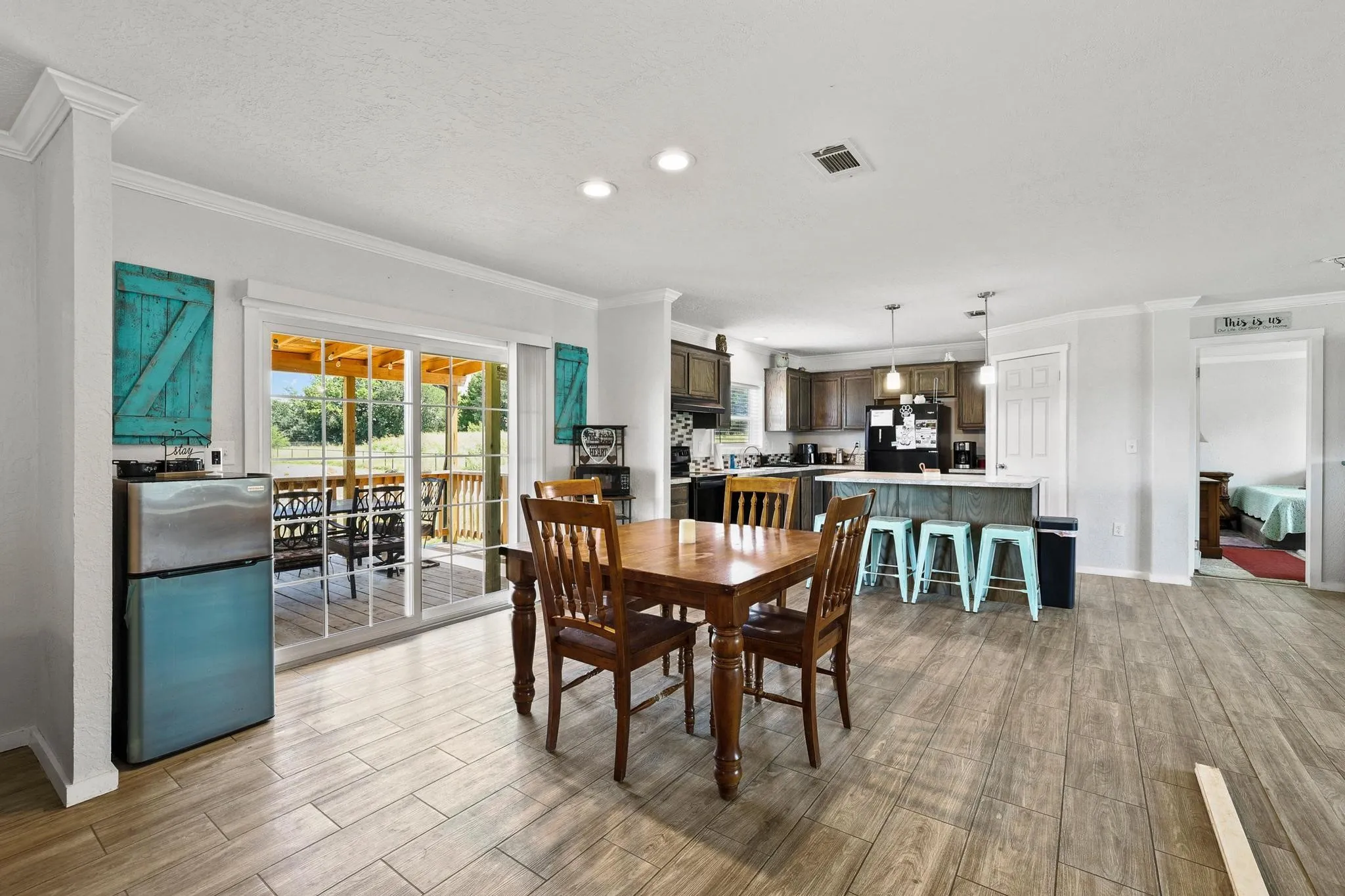 Spacious interior featuring wood-finish flooring, a kitchen with dark cabinetry and an island, a dining area, and a sliding glass door opening to an outdoor deck