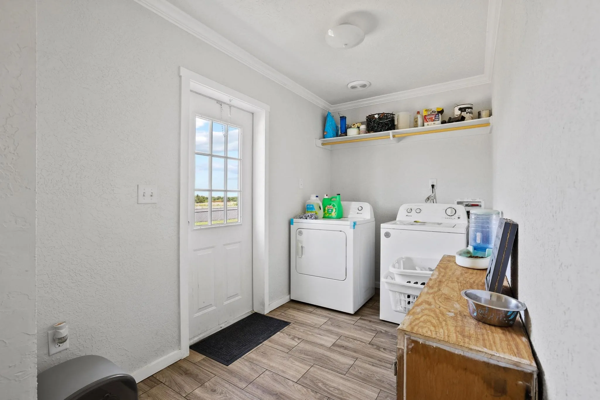 Dedicated laundry space featuring wood-finish flooring, white walls, and a glass-paneled exterior door