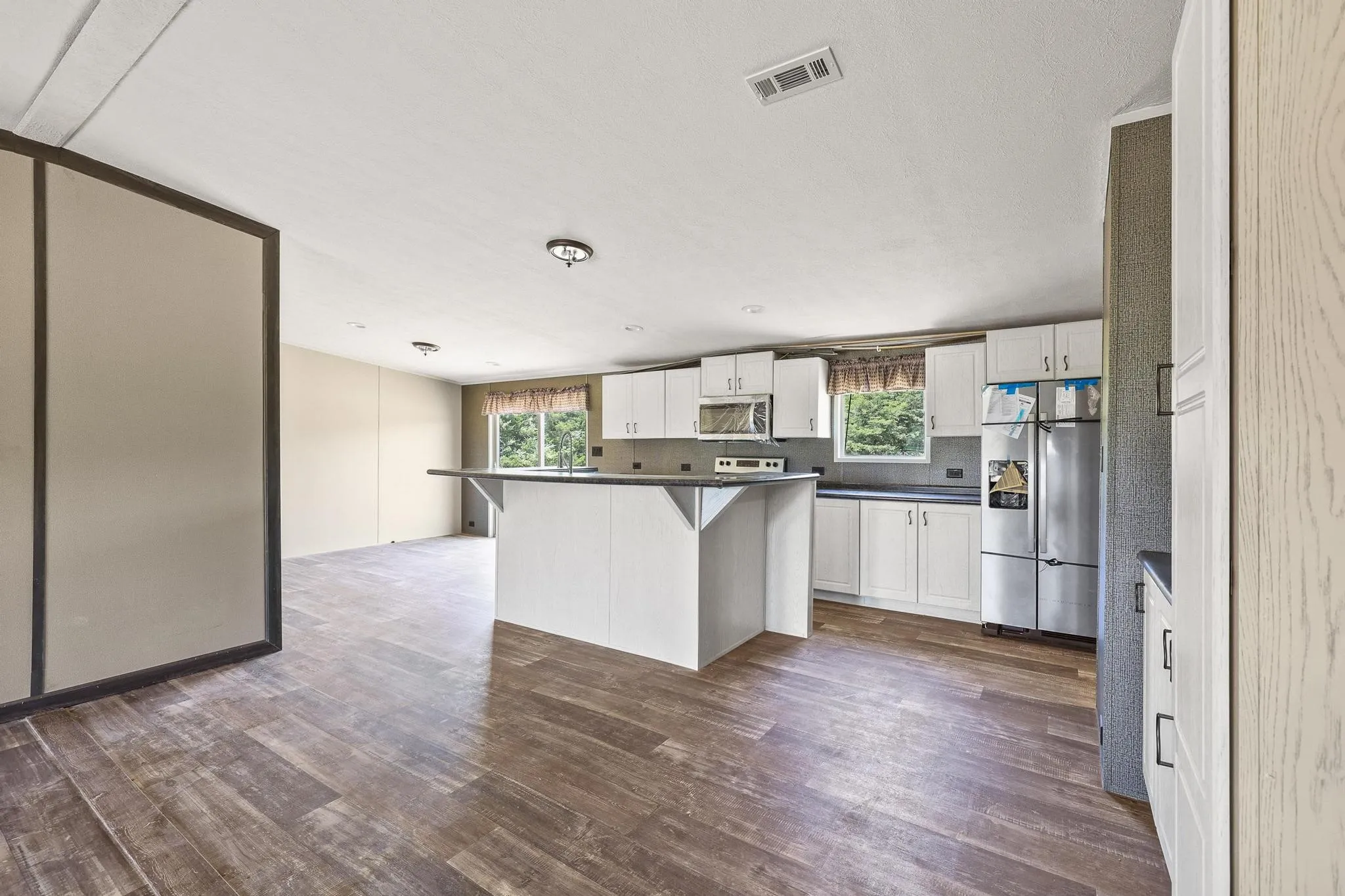 Kitchen featuring wood-finish flooring, white cabinetry, dark countertops, and stainless steel appliances