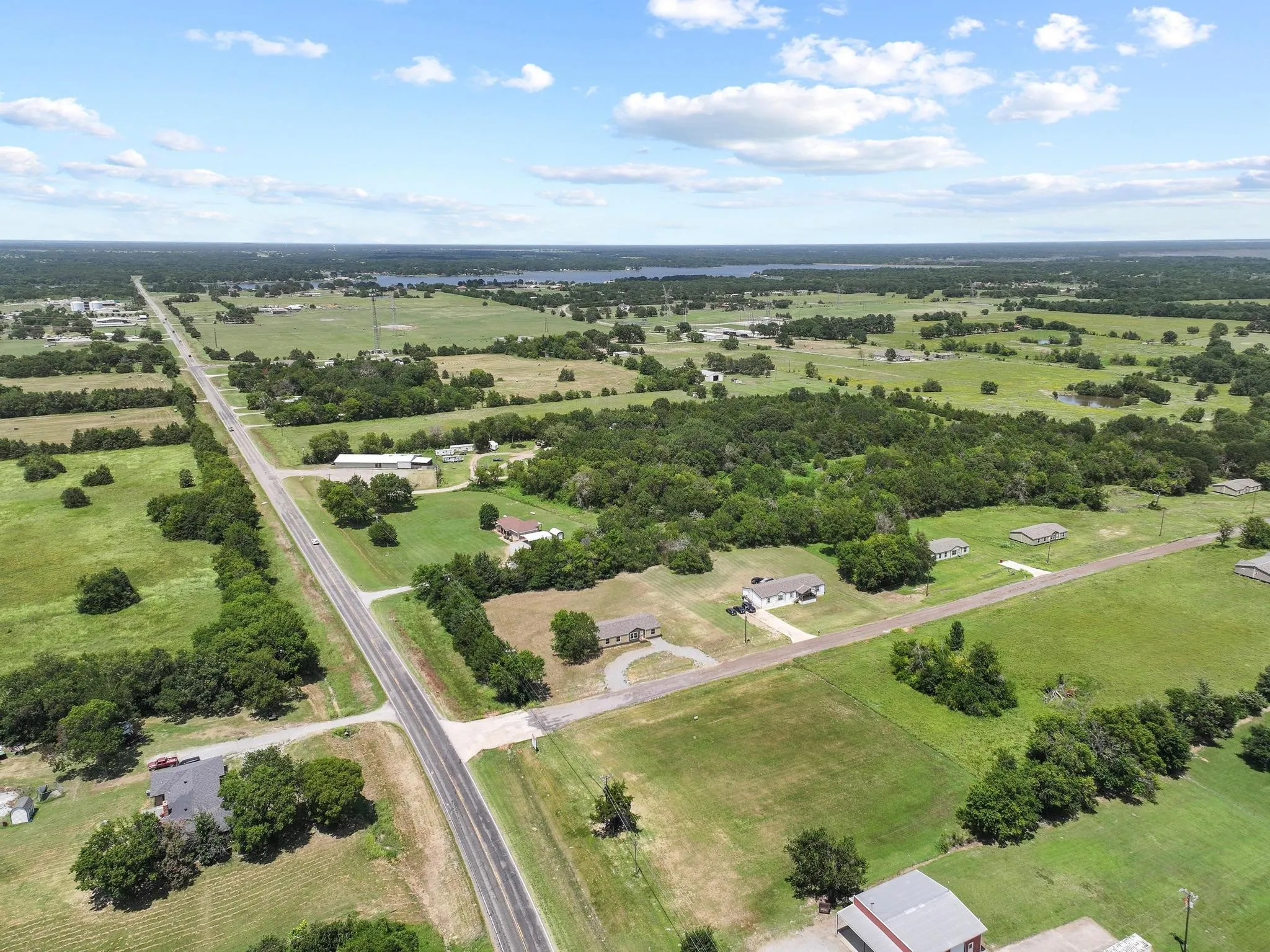 Expansive rural landscape featuring a highway traversing green fields and scattered trees