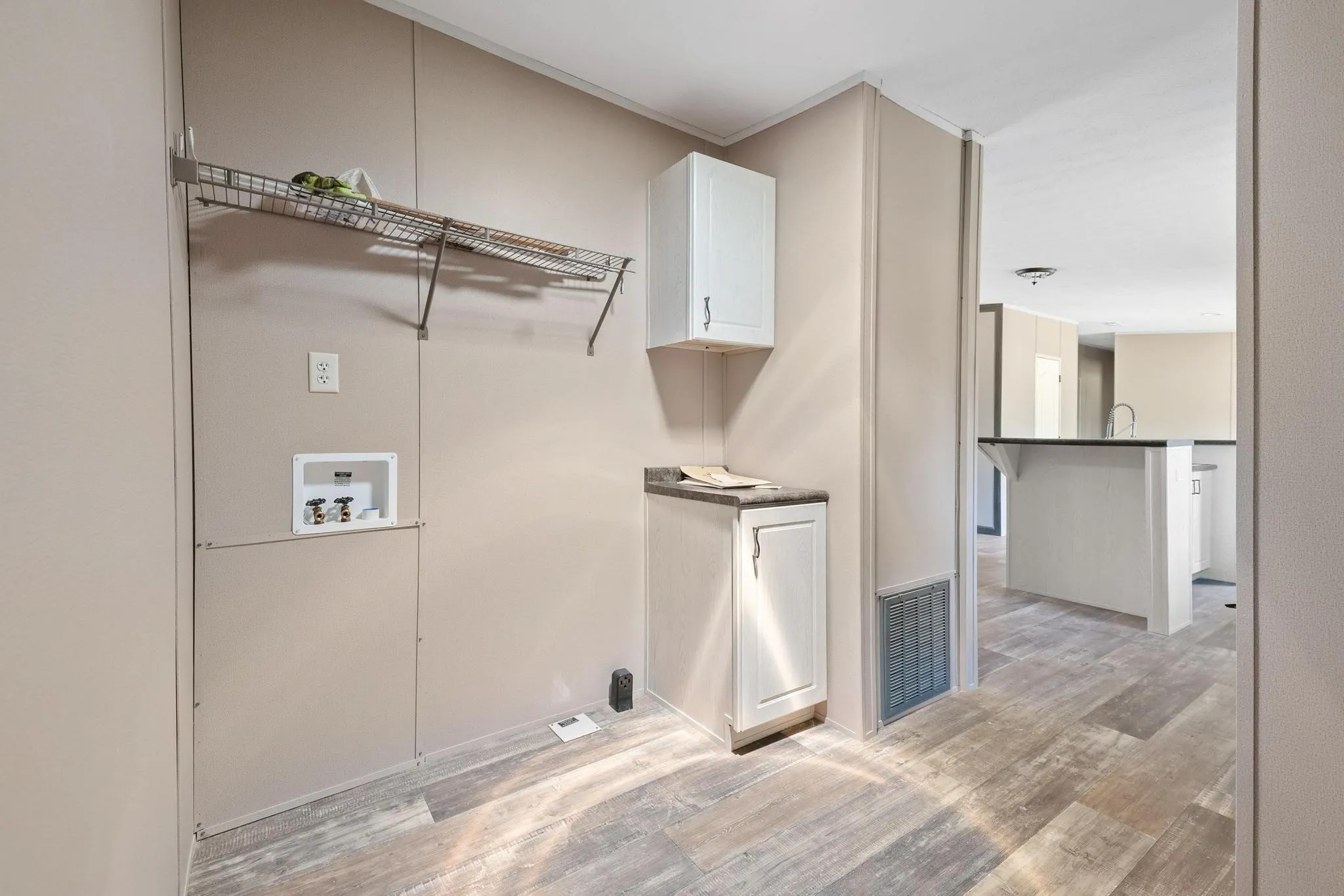 Dedicated laundry area featuring a wire storage shelf, utility hookups, and wood-finish flooring
