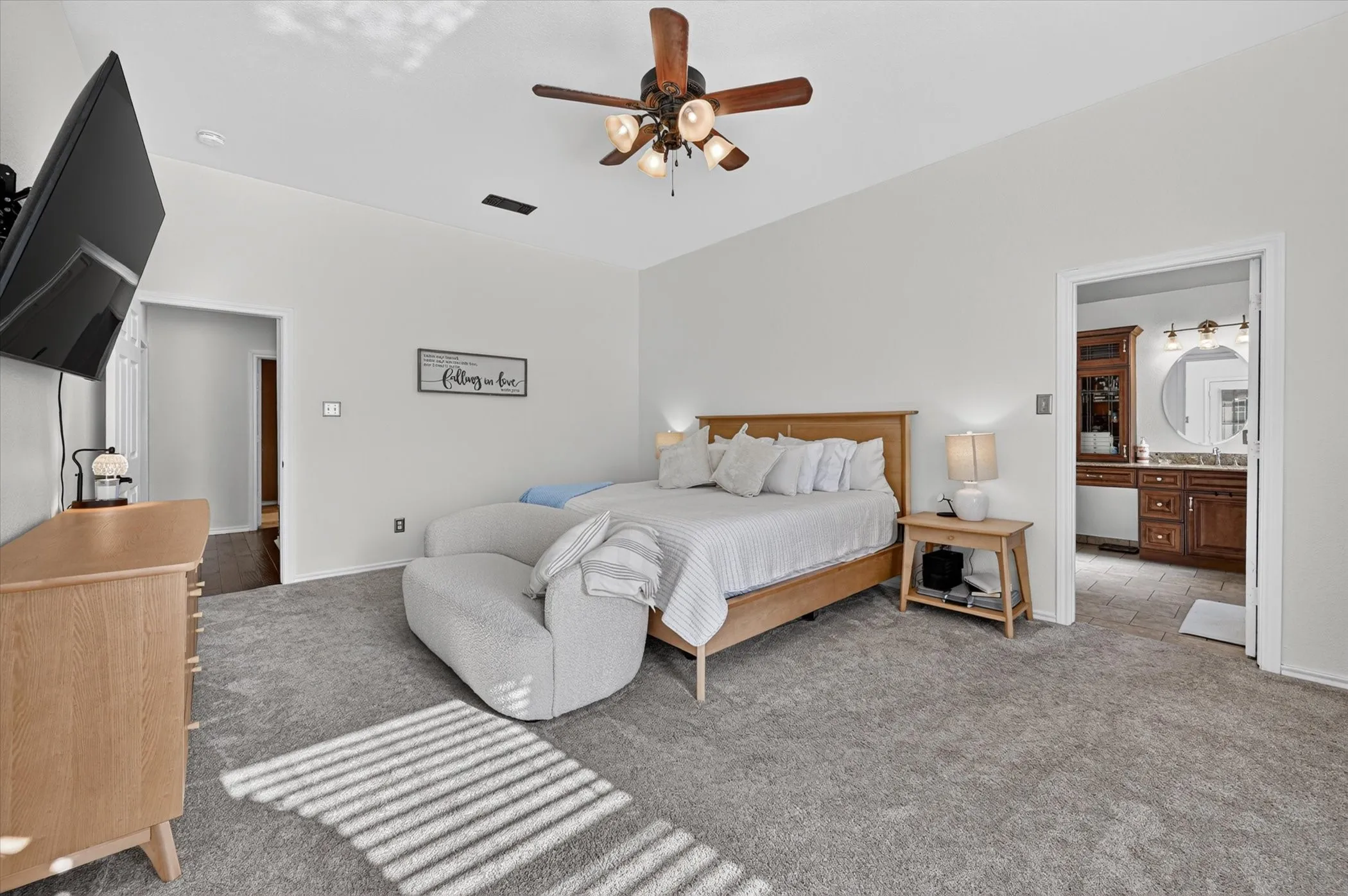 Carpeted bedroom with vaulted ceiling and a wood-bladed ceiling fan