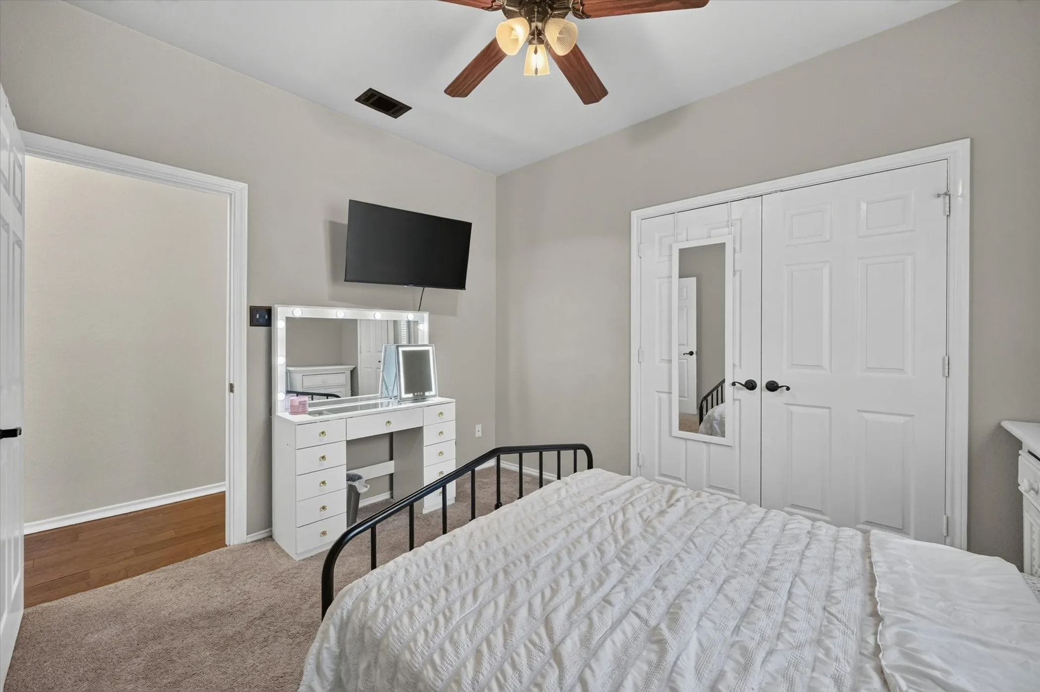 Bedroom featuring carpet flooring, neutral painted walls, white paneled doors, and a ceiling fan