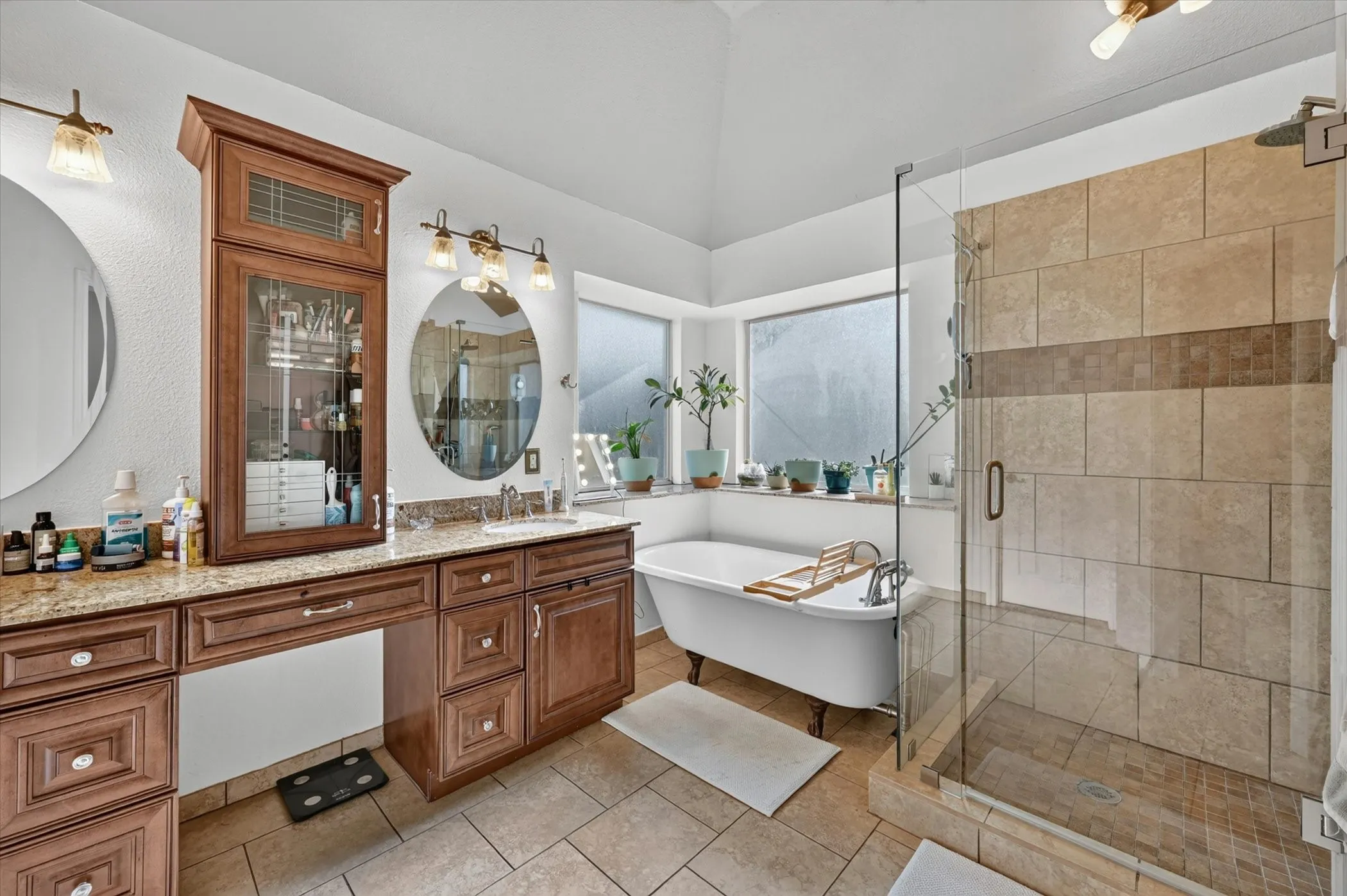 Bathroom featuring a frameless glass shower enclosure, a freestanding clawfoot tub, and a dual vanity with a built-in storage cabinet