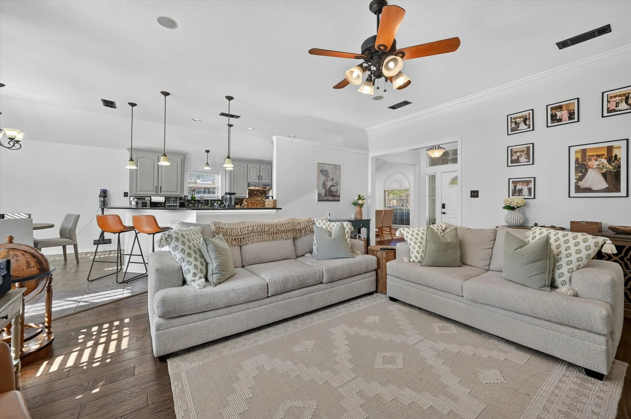 Open-concept living area featuring rich wood-finish flooring, a contemporary ceiling fan with lighting, and recessed overhead lighting