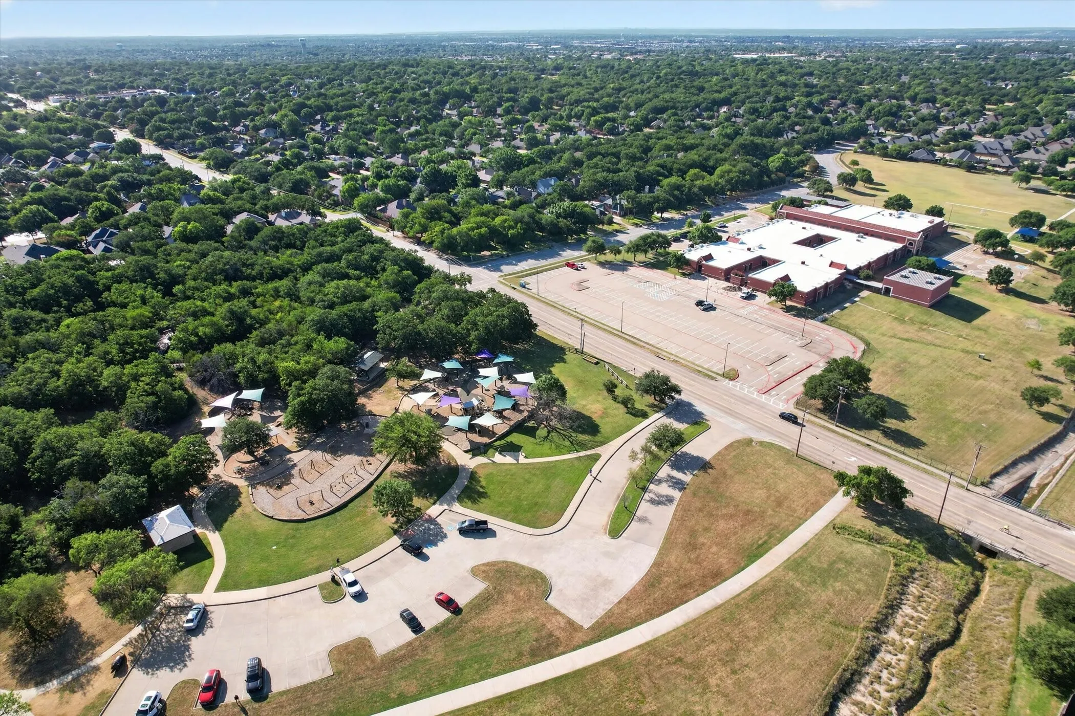 Expansive green spaces featuring mature tree coverage, paved roadways, and community buildings