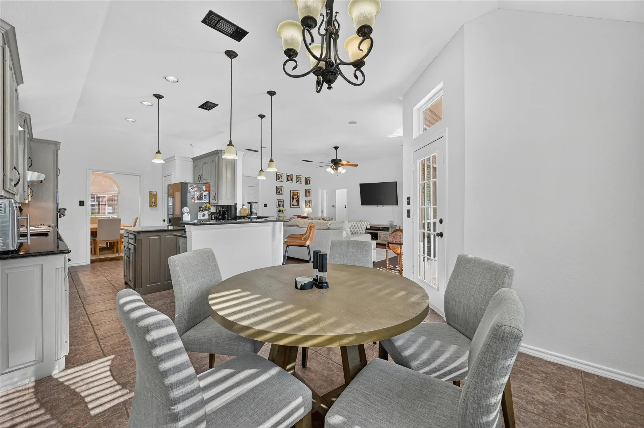 Open-concept kitchen and dining area featuring tile flooring, white walls, and a multi-light chandelier