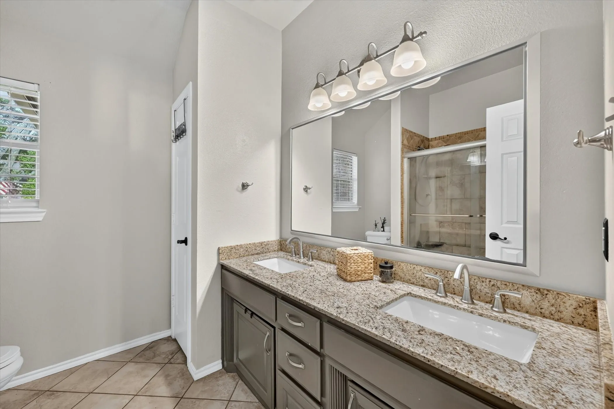 Bathroom featuring a dual vanity with granite countertops, undermount sinks, and brushed nickel fixtures