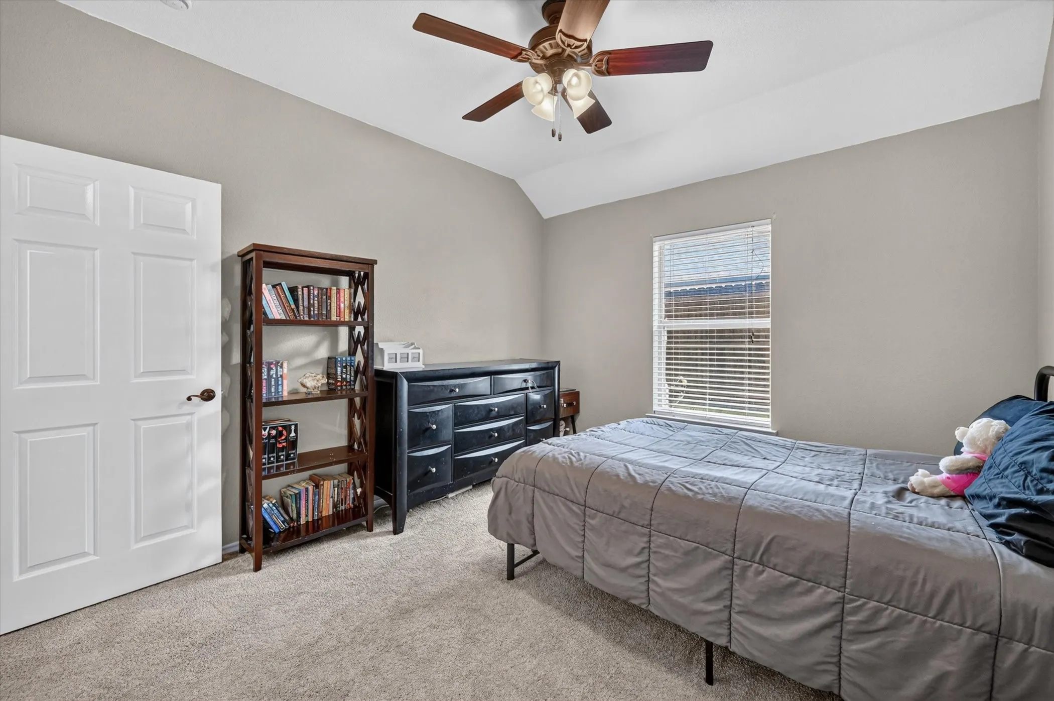 Room featuring neutral-toned walls, vaulted ceilings, and plush carpeting