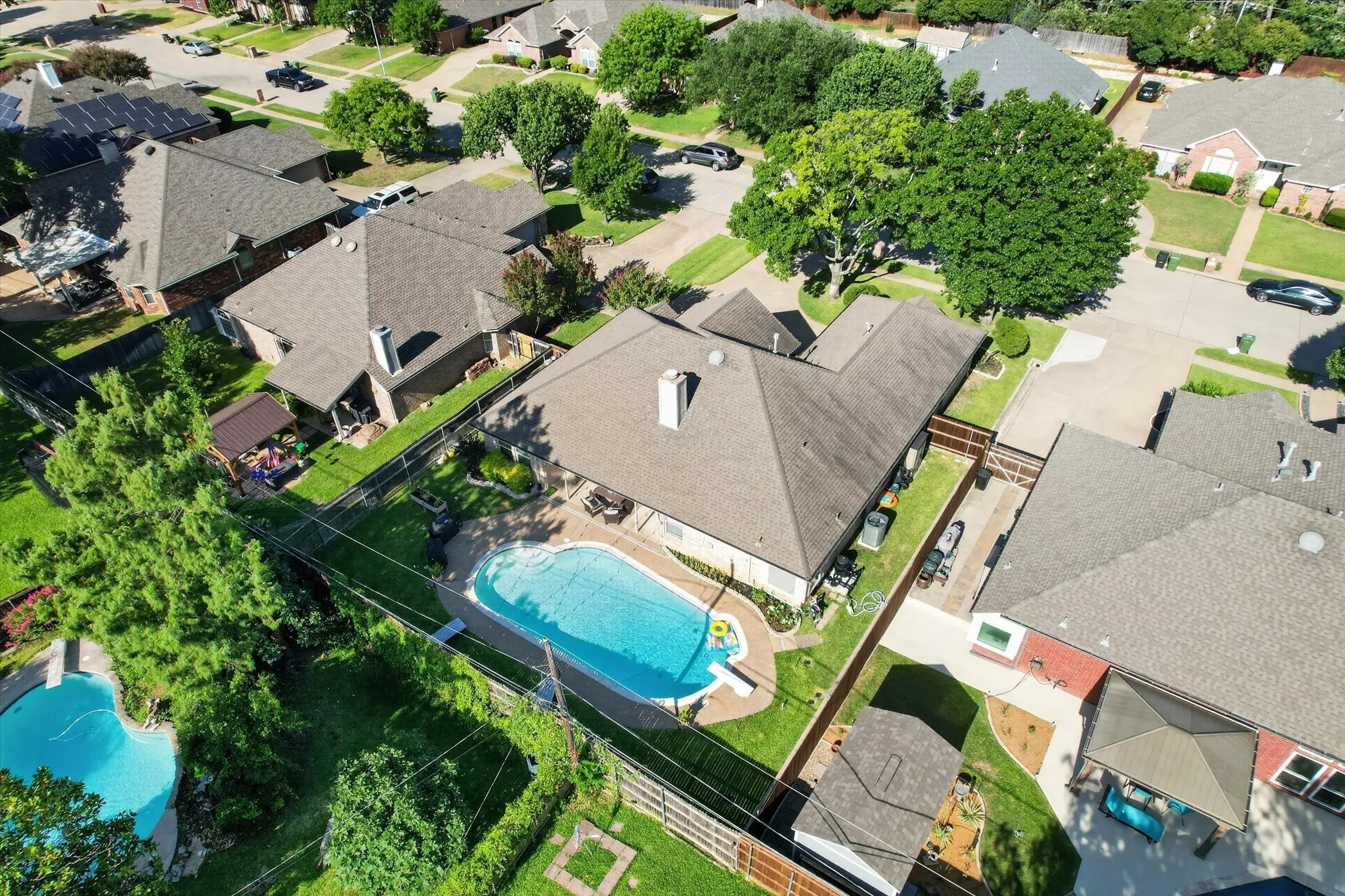 Rear exterior featuring a large in-ground swimming pool, surrounding concrete patio, and a privacy fence