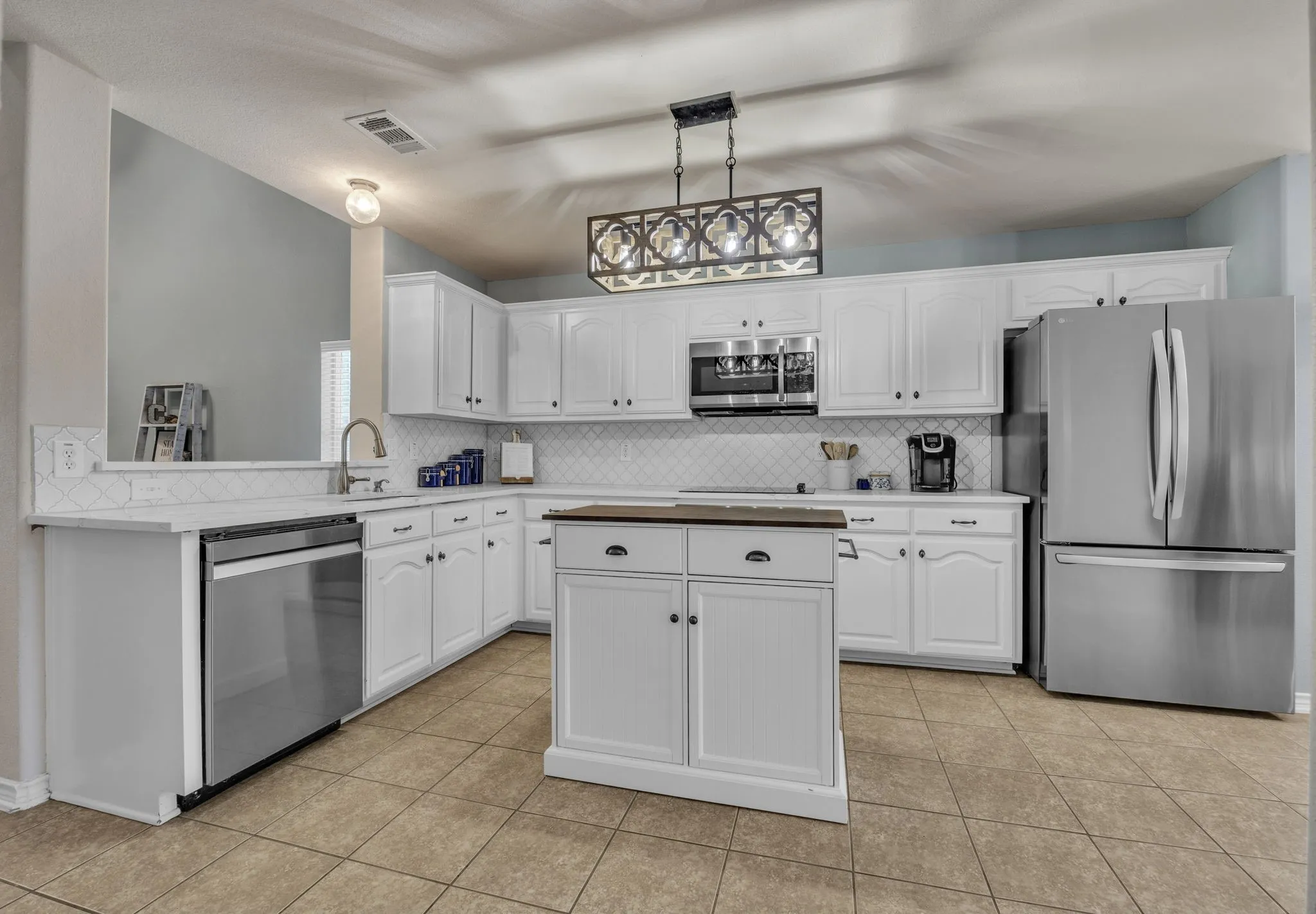 Renovated kitchen with quartz countertops, stainless steel appliances, backsplash, and new lighting.