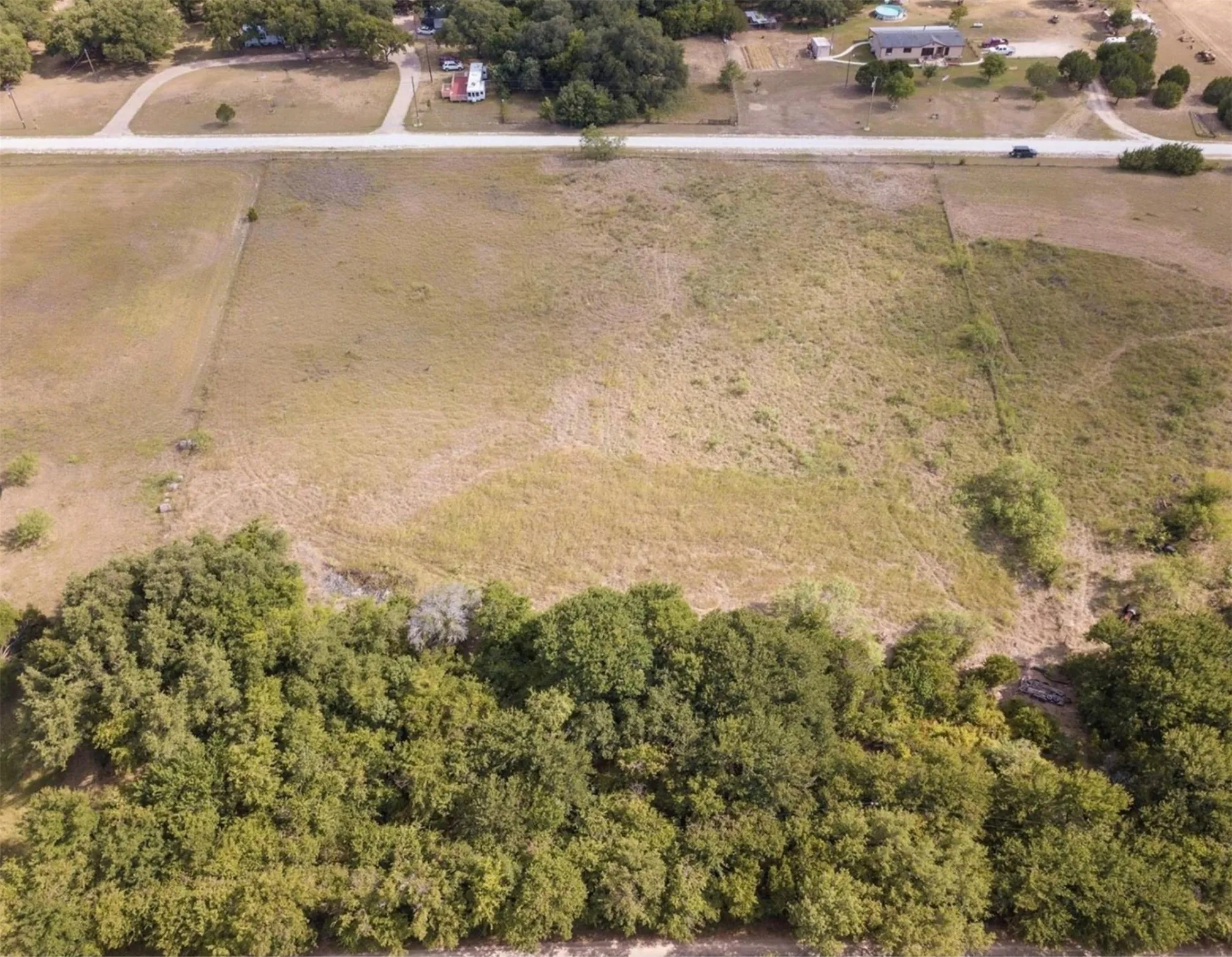 Expansive undeveloped land featuring a mix of open grassy areas and dense mature trees