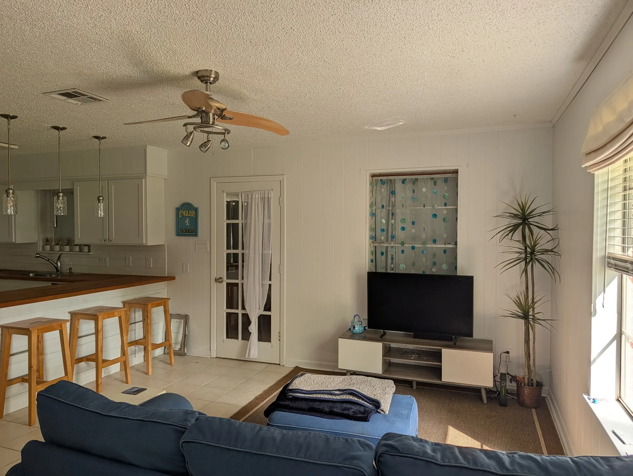 Open-concept interior featuring light-colored wall paneling and neutral tile flooring