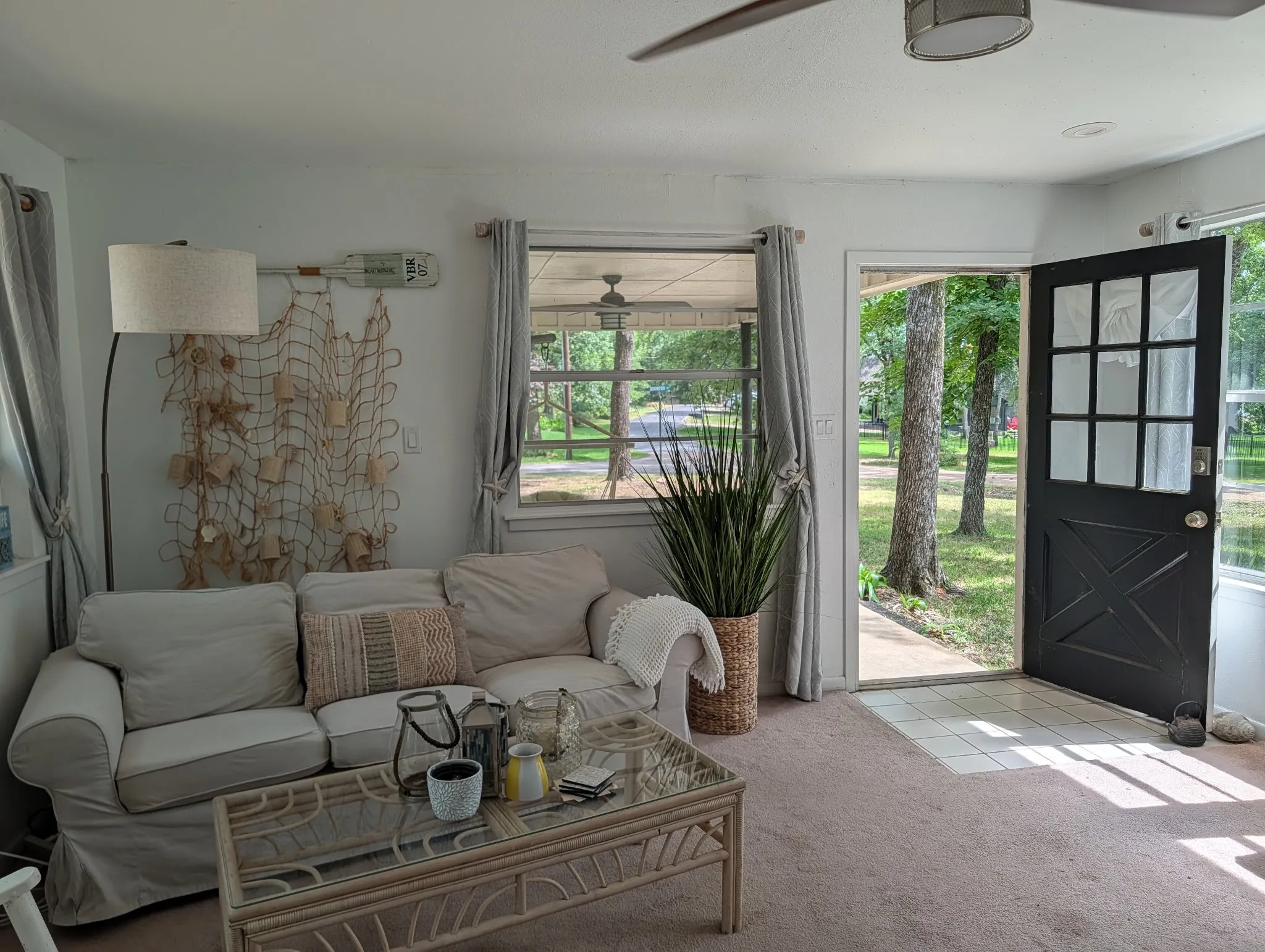 Living area featuring a glass-paned entry door, ceiling fan, and carpet flooring