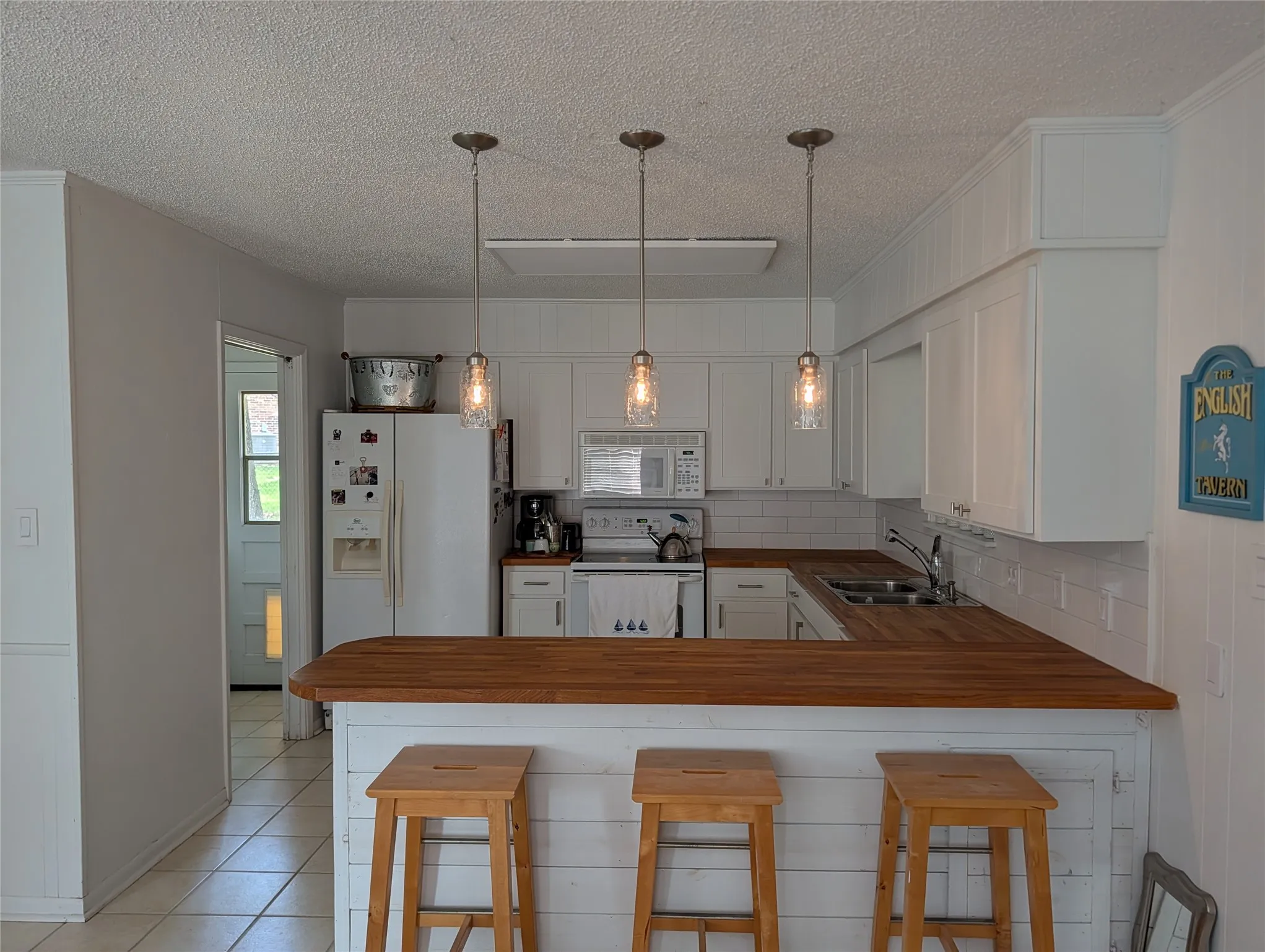Kitchen featuring white cabinetry, subway tile backsplash, and wood-finish countertops
