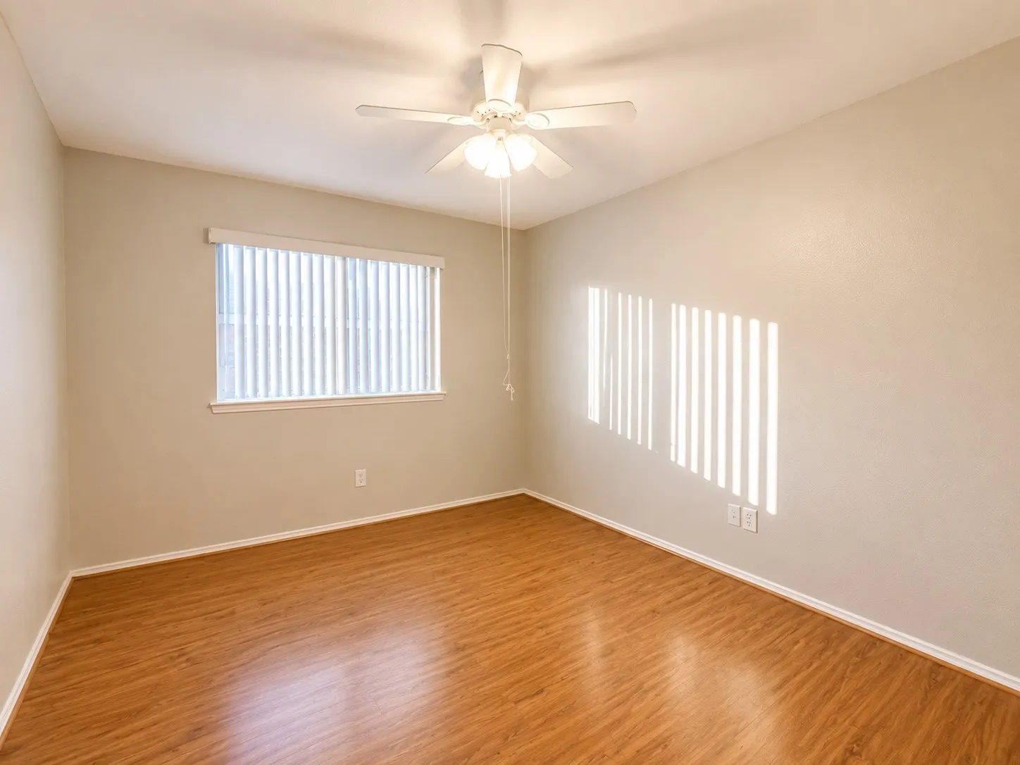 Room featuring wood-finish flooring, a window with horizontal blinds, and a ceiling fan with integrated lighting