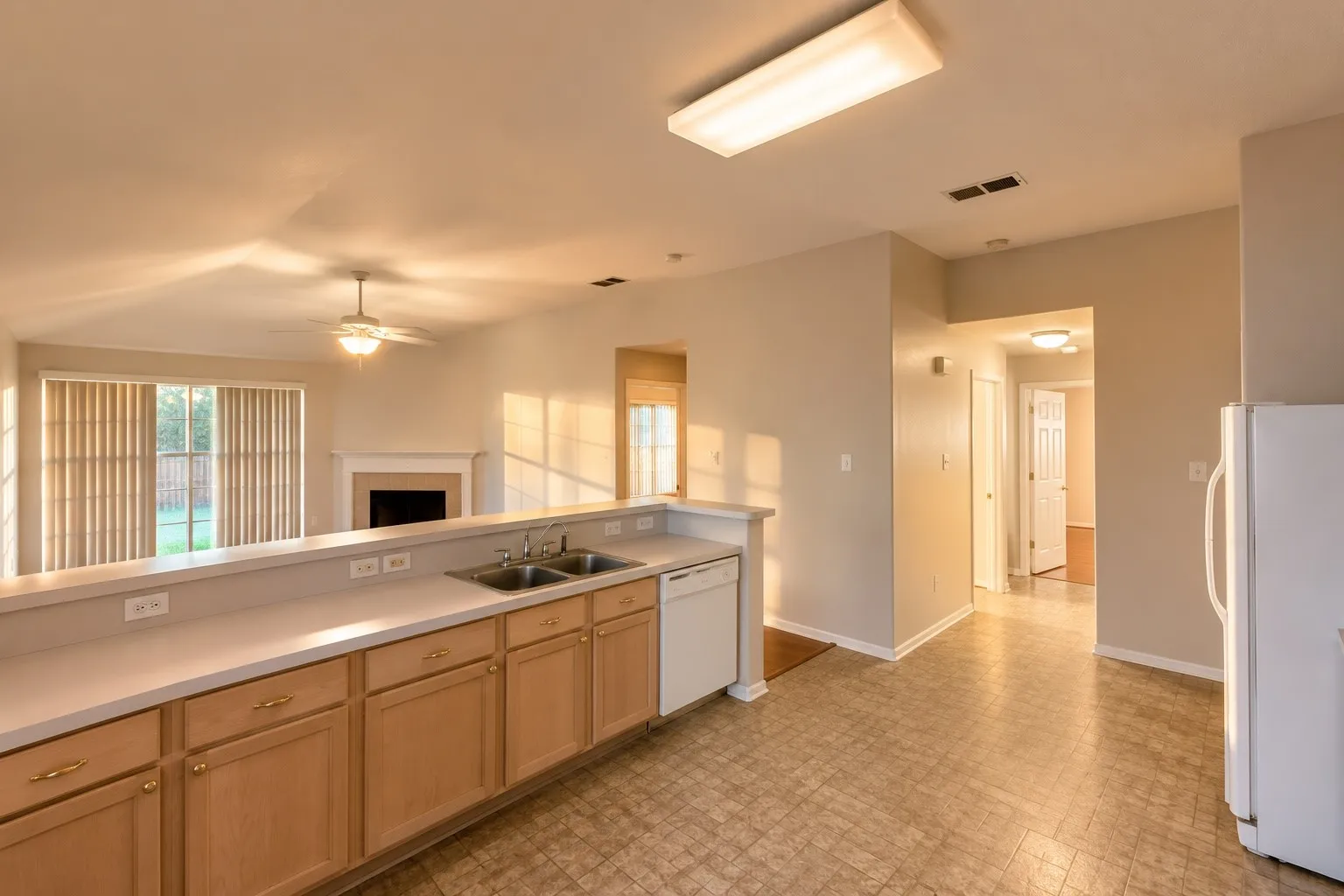 Kitchen featuring light wood-finish cabinetry, white countertops, and a double basin sink