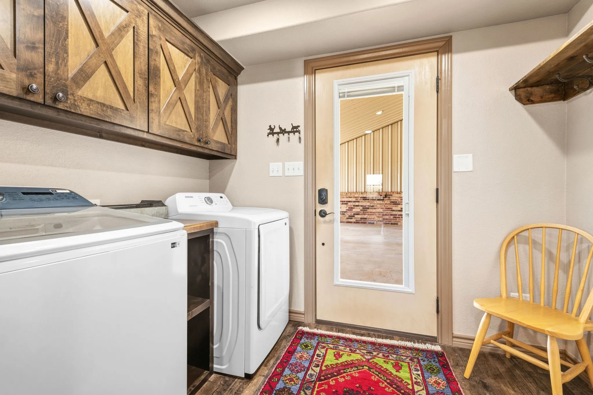 Laundry room offers custom X-brace cabinetry for storage, plus direct access outside-practical, rustic charm that carries the barndominium style throughout.