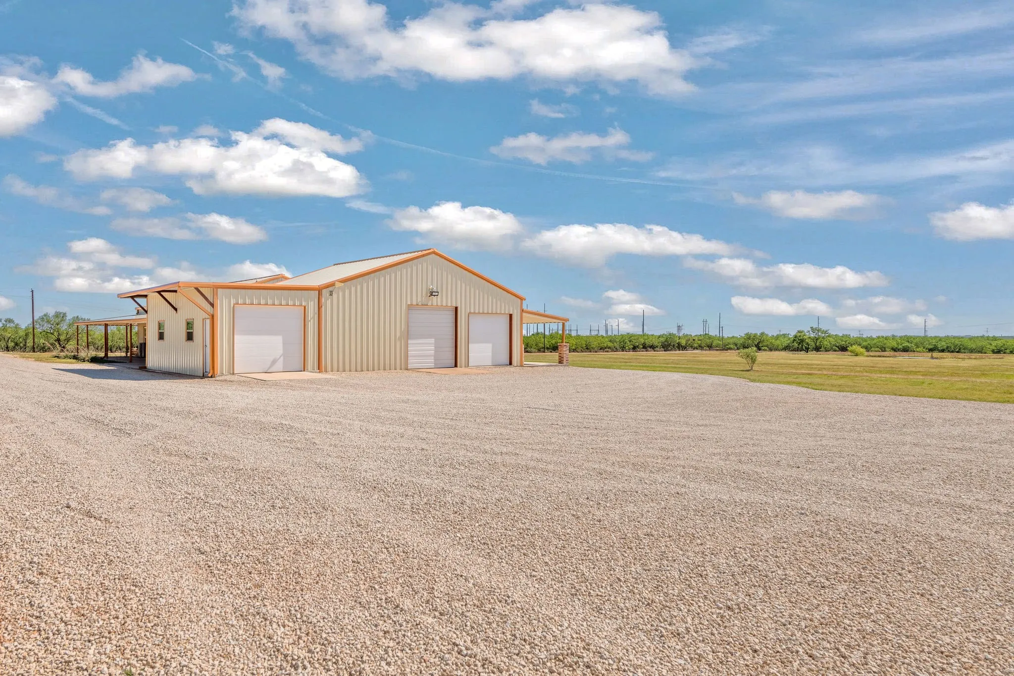 80'x100' caliche parking area. View of side of 30'x40' shop with added 15' x 30' workshop addition and 3 bay doors.