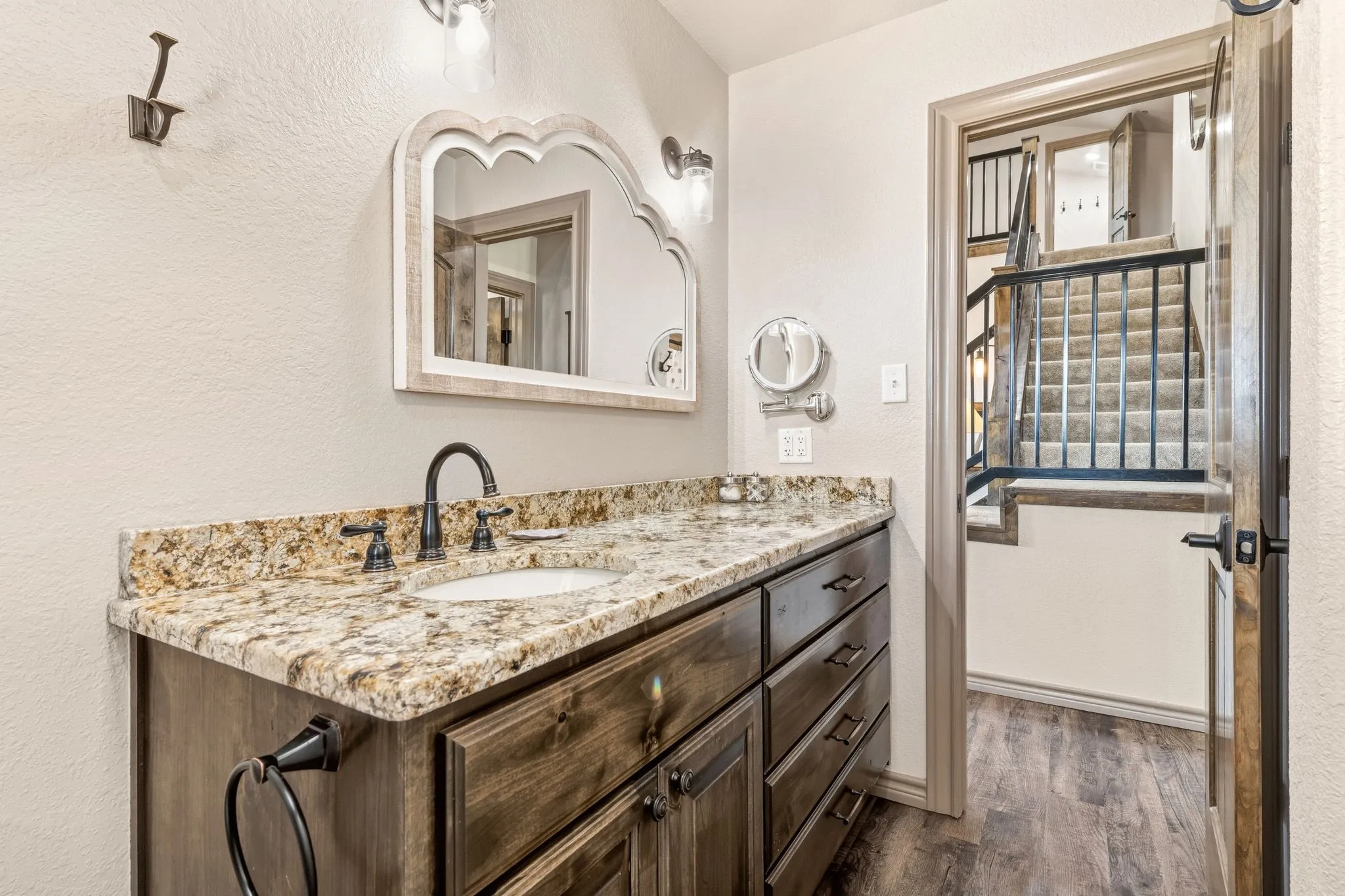 Granite vanity, dark wood cabinetry, a rechargeable LED makeup mirror with an extendable arm make this guest bathroom both functional and stylish.