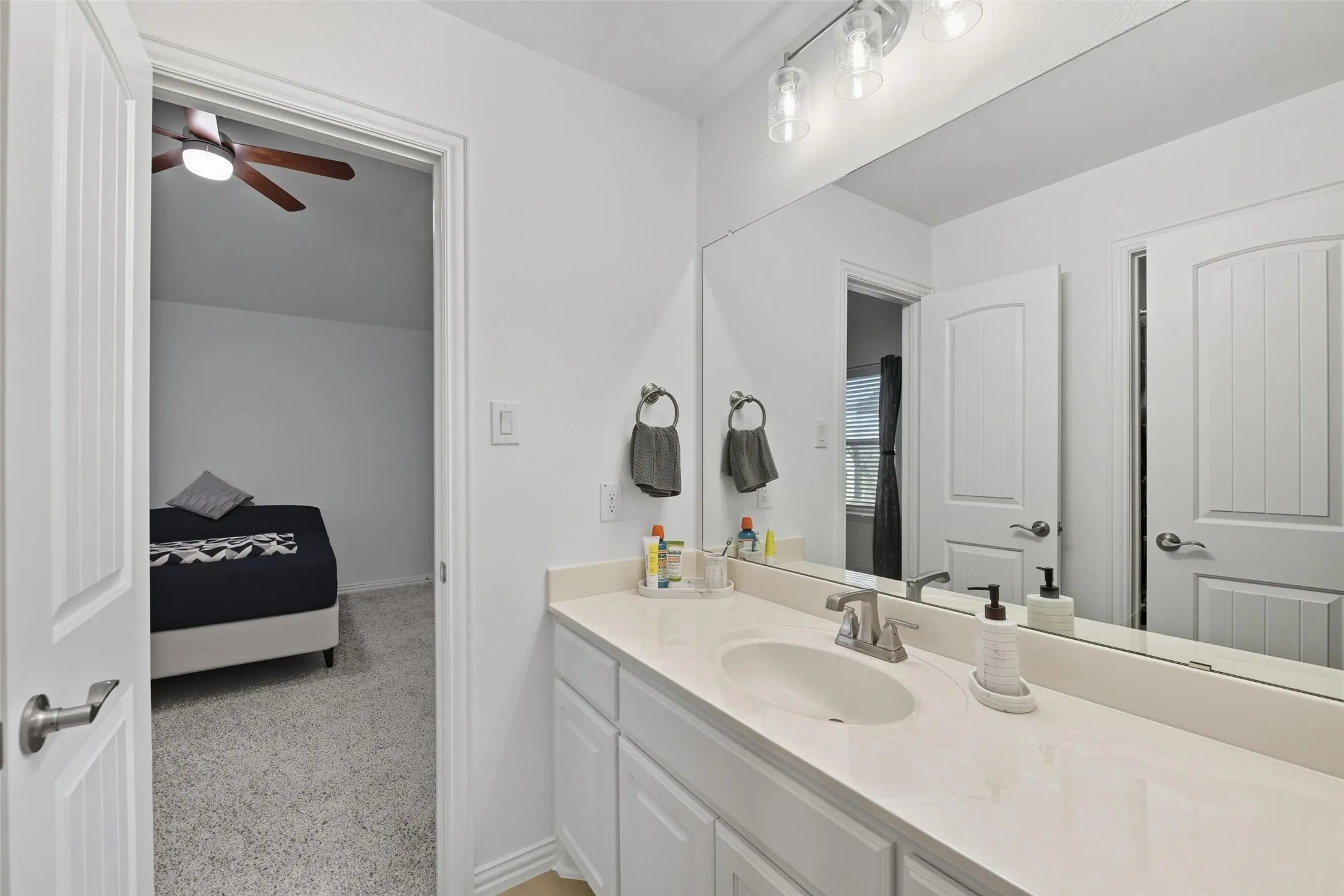 Bathroom featuring a white vanity with an integrated sink, brushed nickel faucet, and a large wall-mounted mirror
