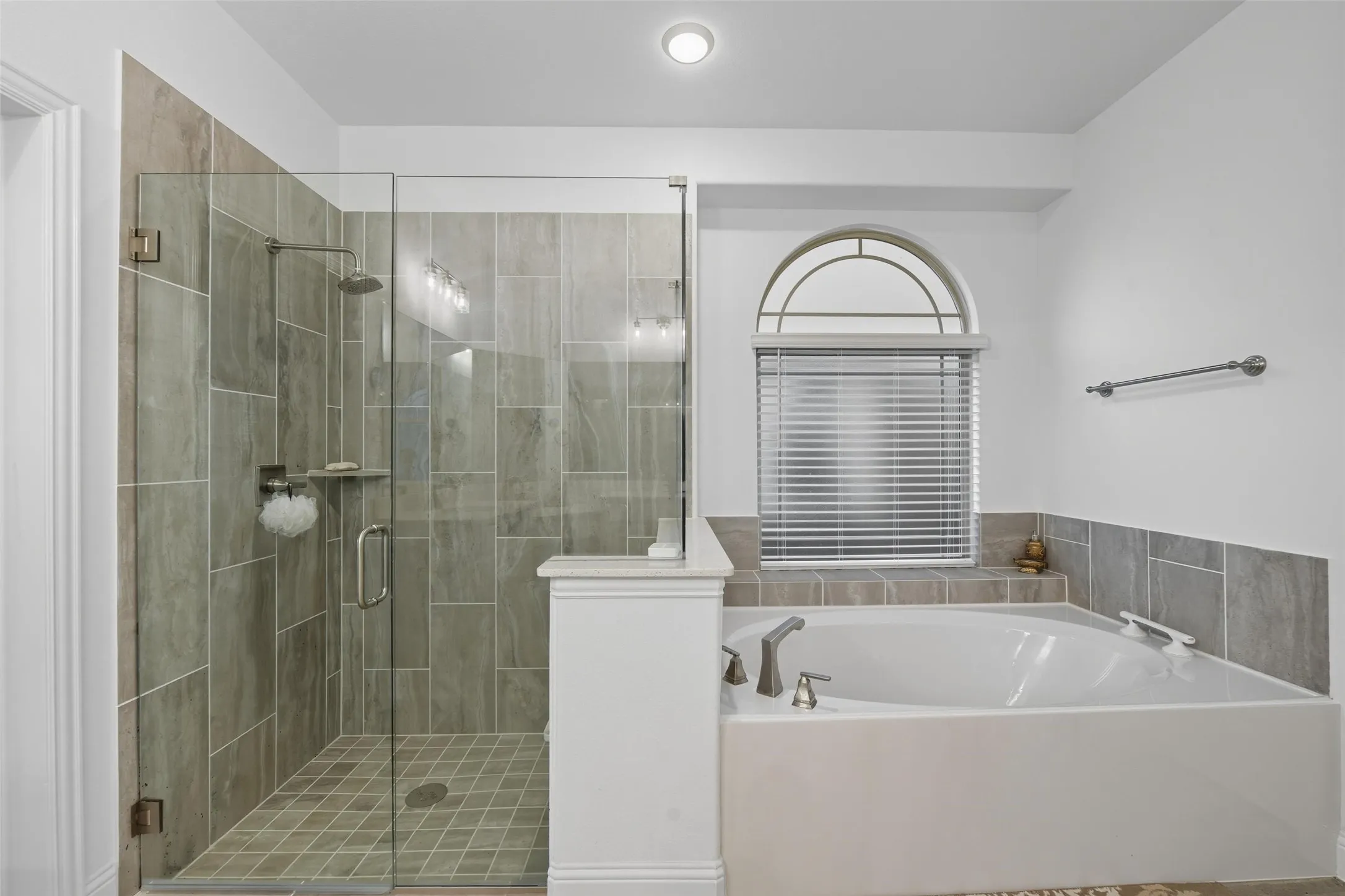 Walk-in shower with full glass enclosure and coordinating tile surround, complemented by a built-in soaking tub with deck-mounted fixtures
