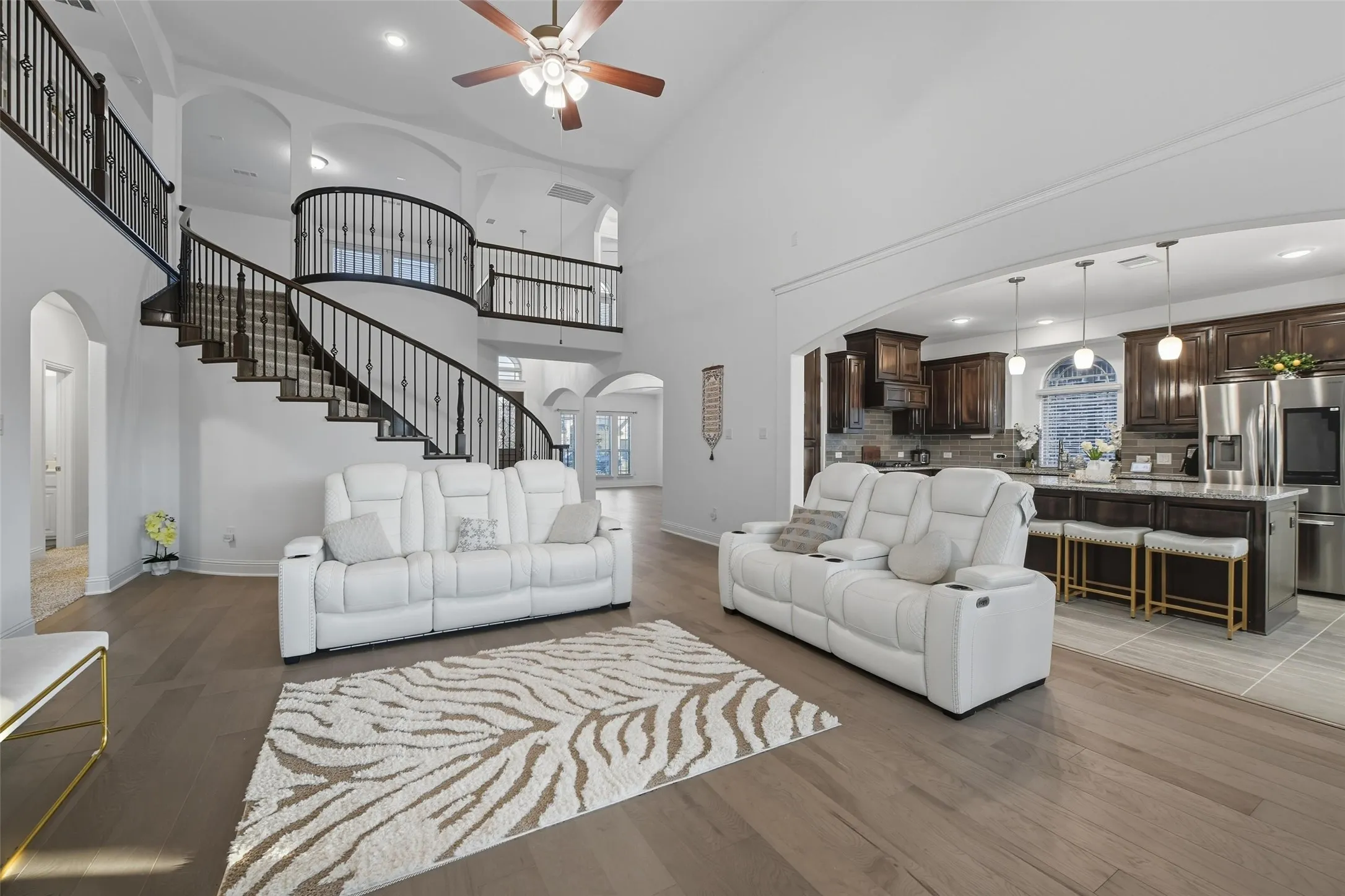 Grand living area featuring a dramatic curved staircase with wrought iron balusters and wood-finish flooring