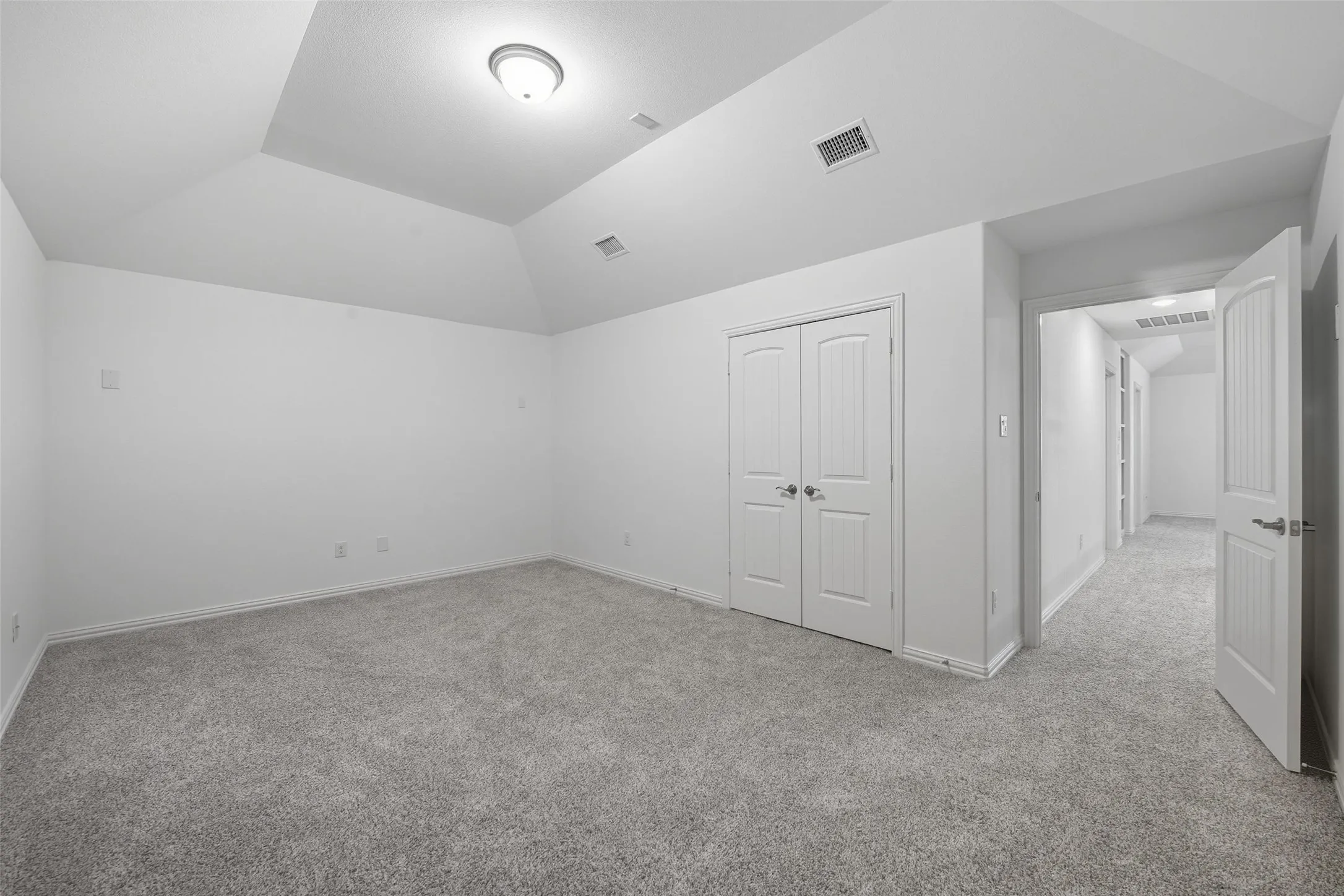 Carpeted room featuring a tray ceiling with a flush-mount light fixture